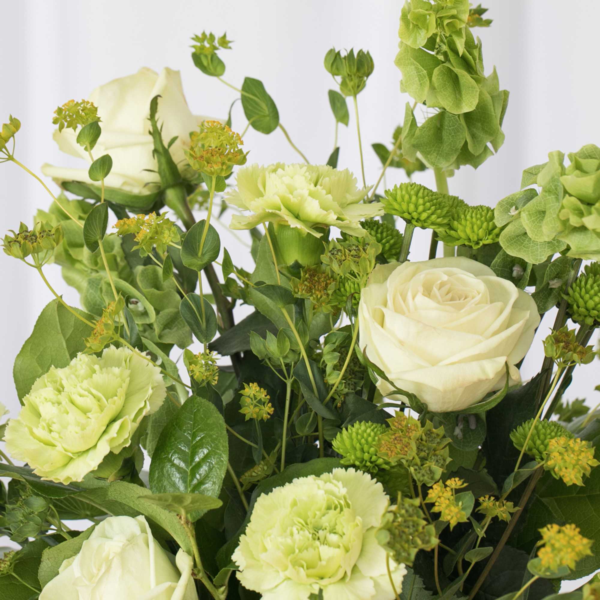 Arrangement of pale green carnations, white roses, and green blooms in a soft monochromatic palette