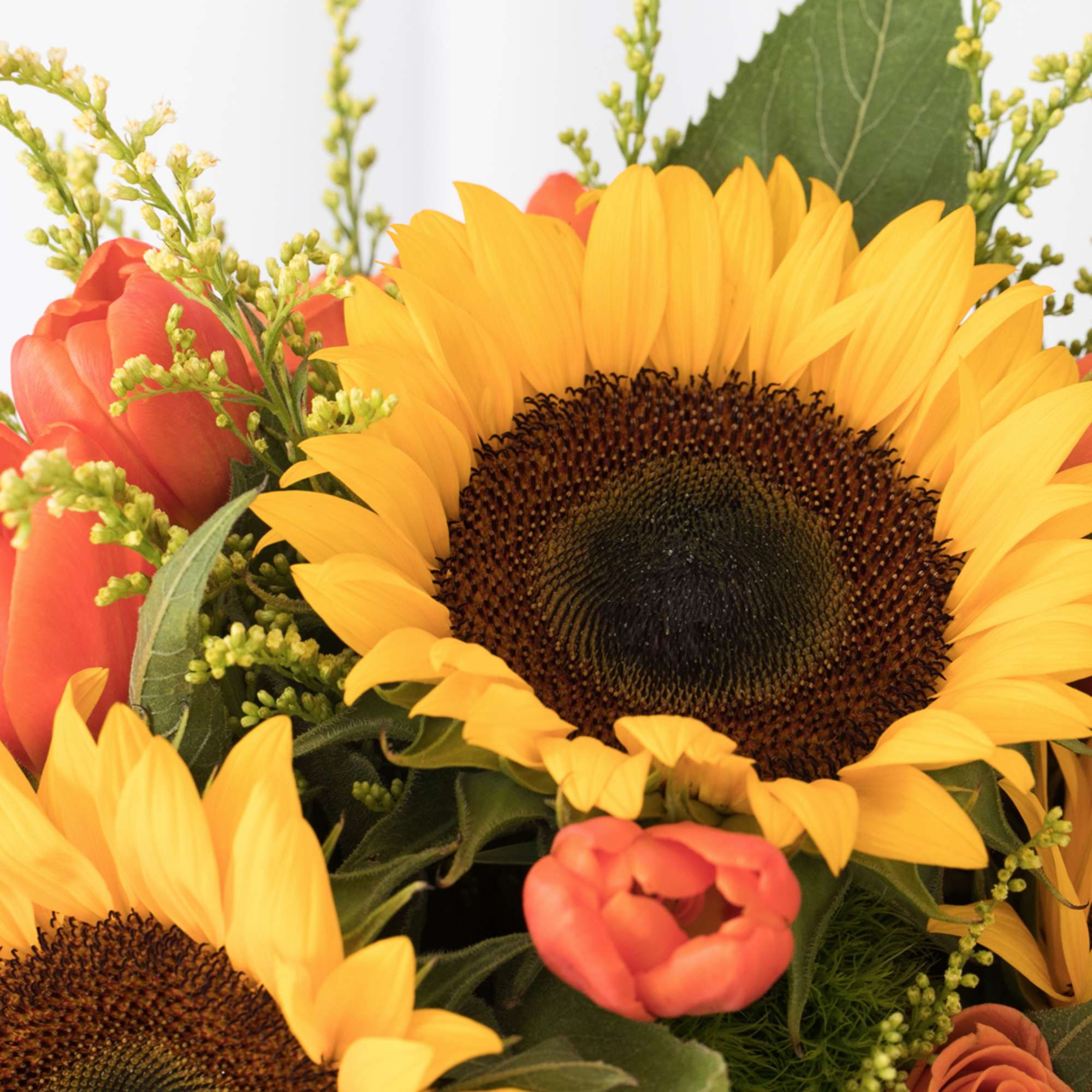 Close-up of yellow sunflowers and orange blooms clustered in a bright arrangement