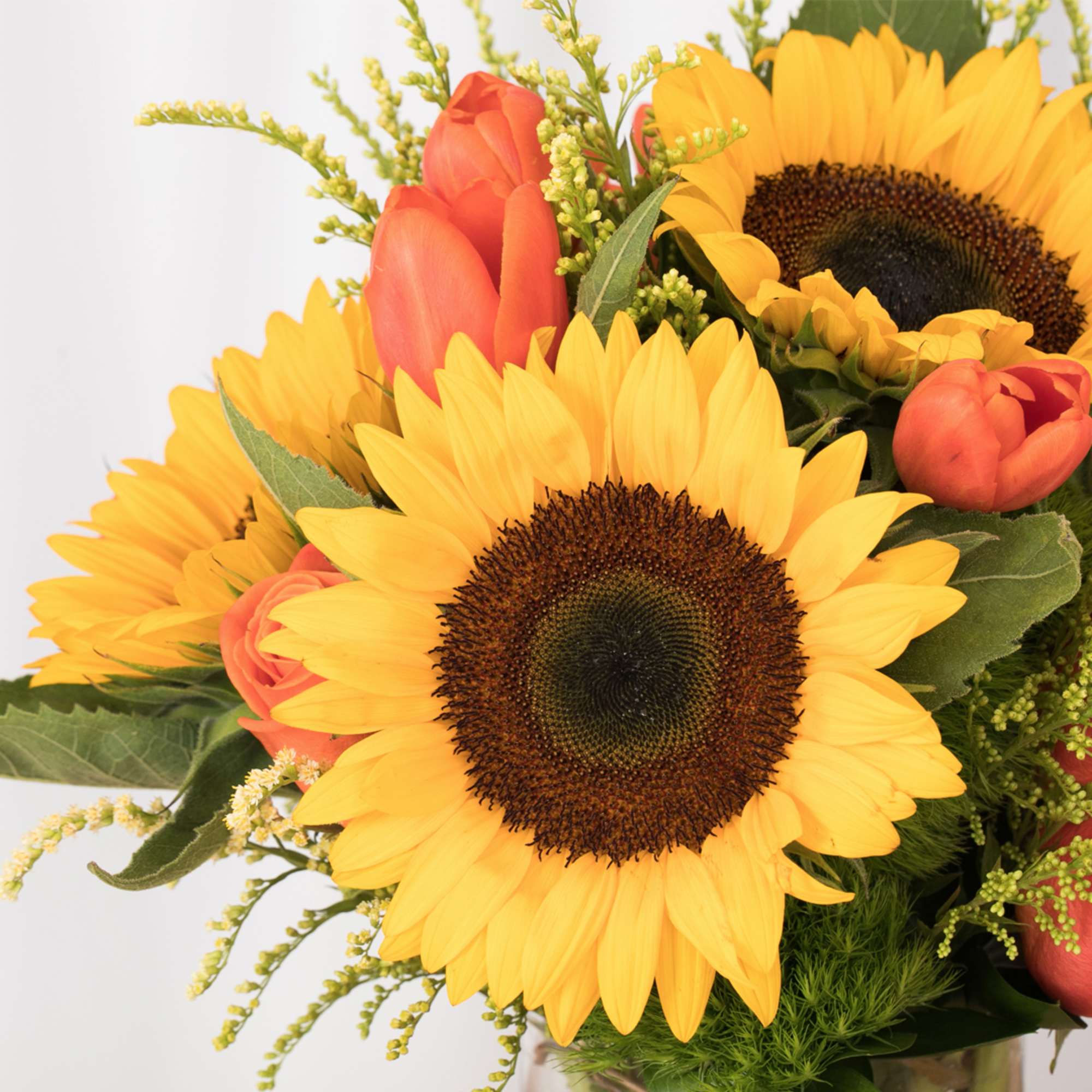 Arrangement of bright yellow sunflowers mixed with orange tulips
