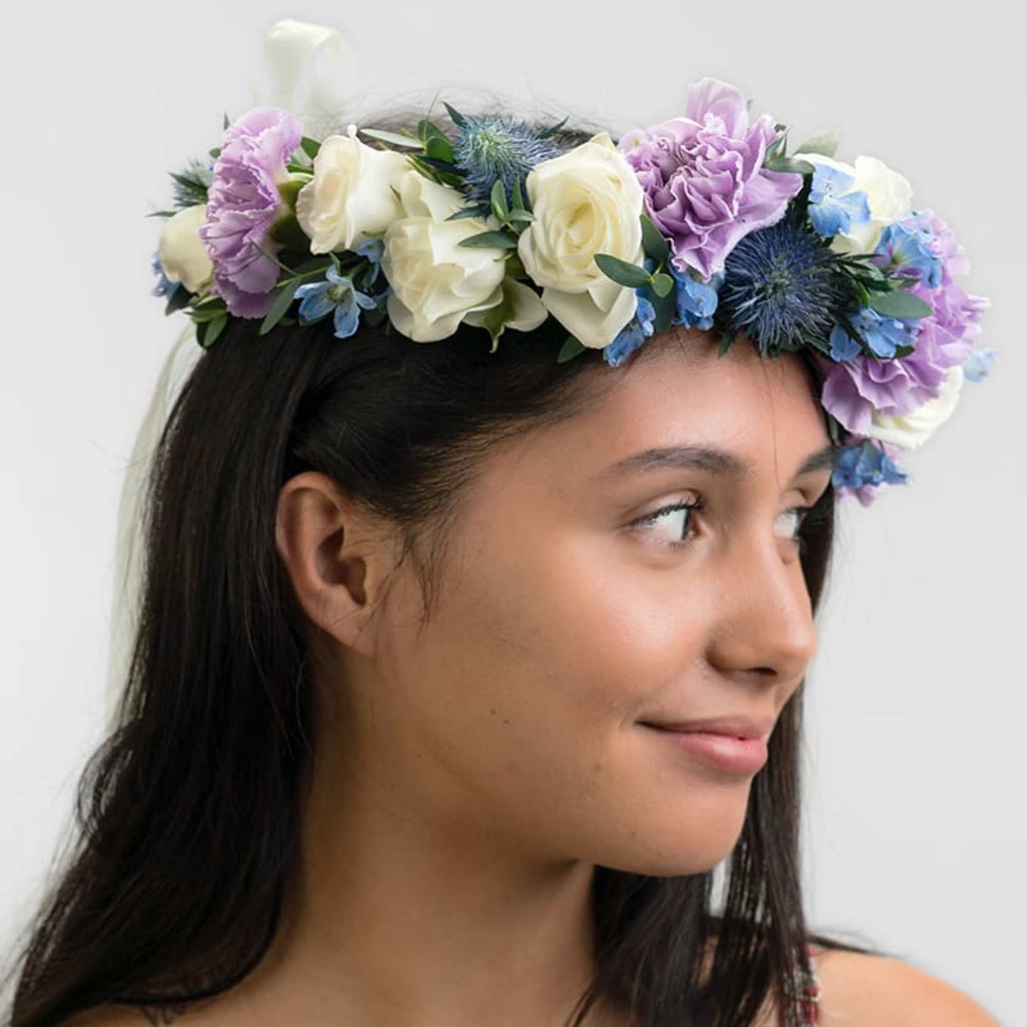 Floral crown of white roses, lavender blooms, and blue flowers worn on a woman’s head