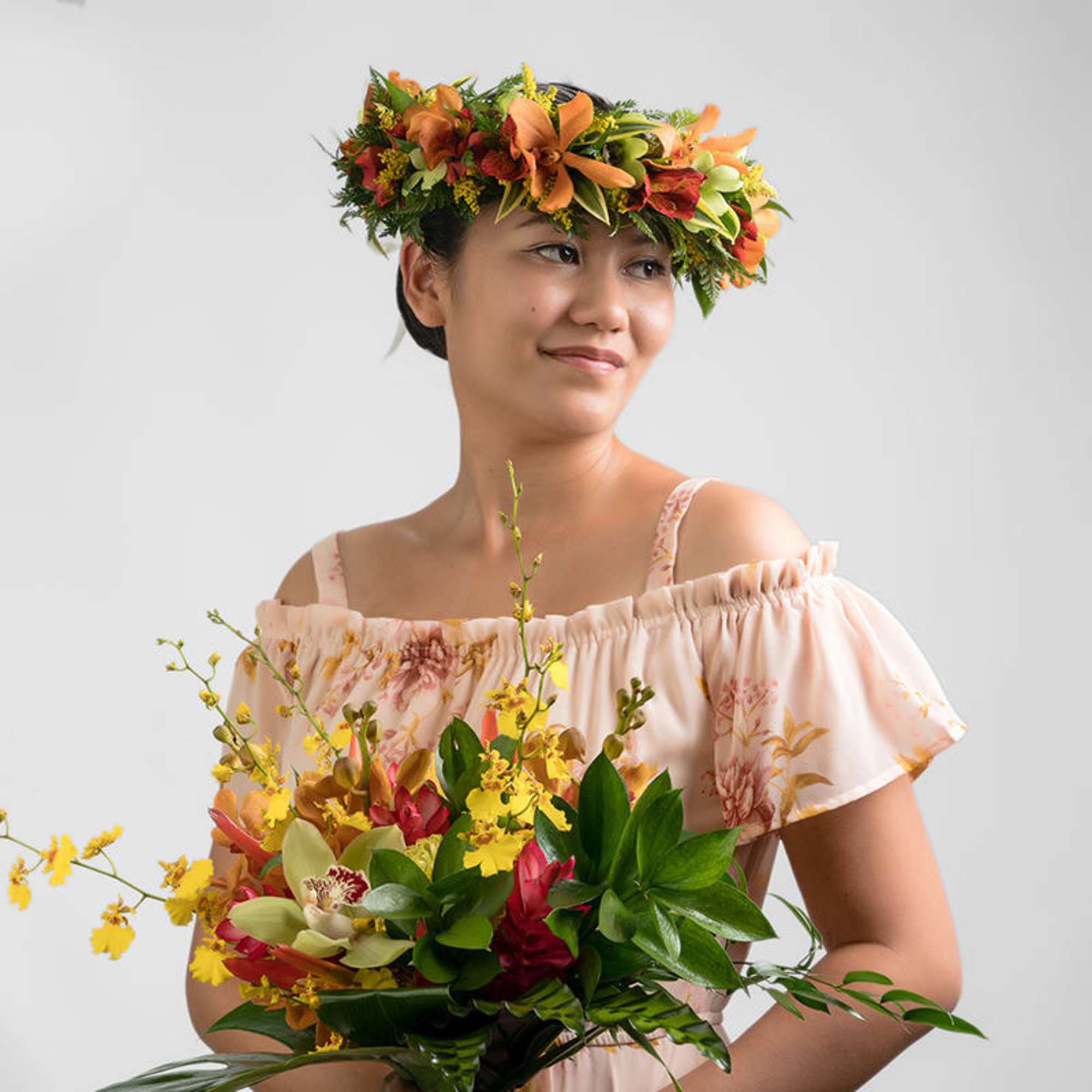 Woman wearing an orange flower crown and holding a tropical bouquet