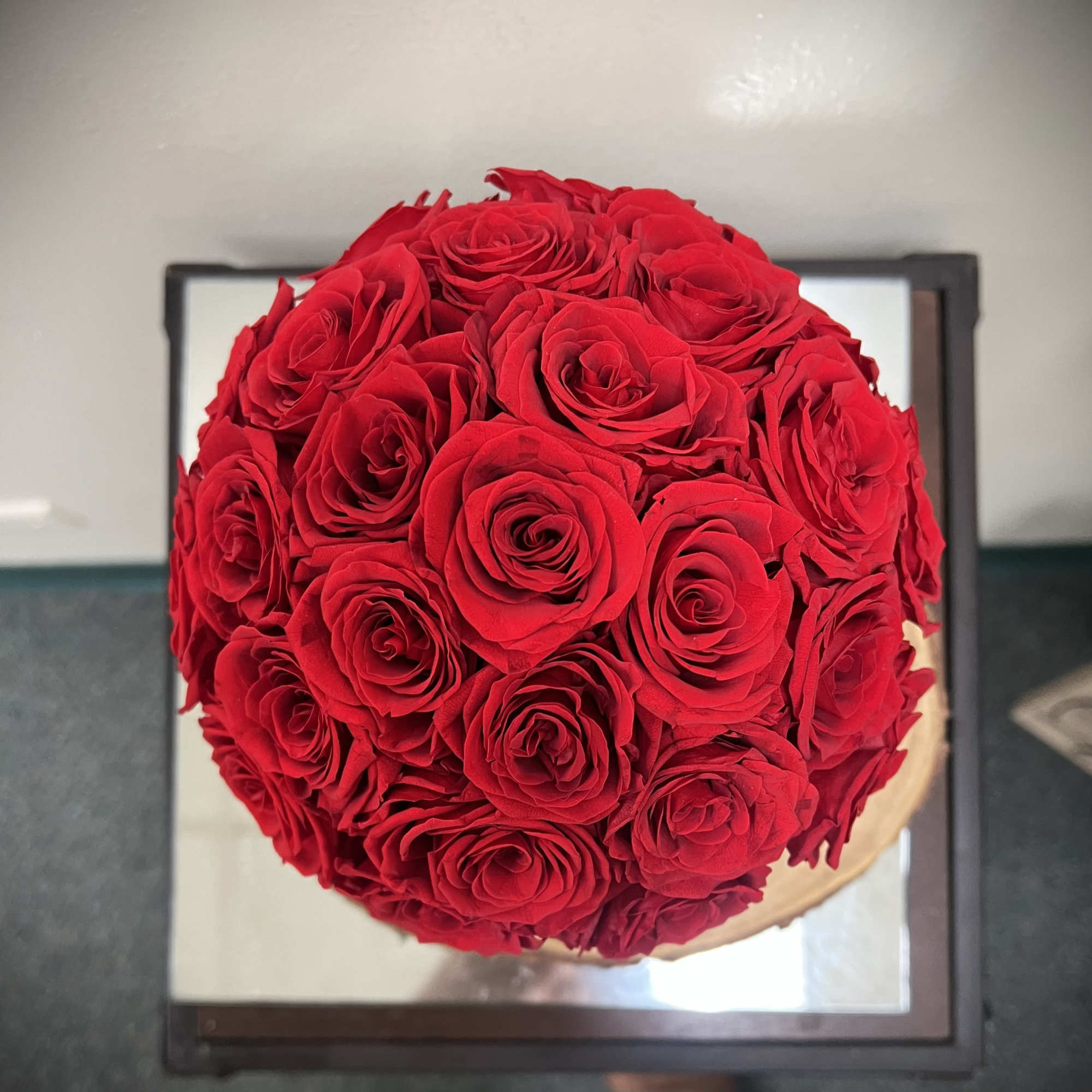 Tight round bouquet of red roses viewed from above on a mirrored surface