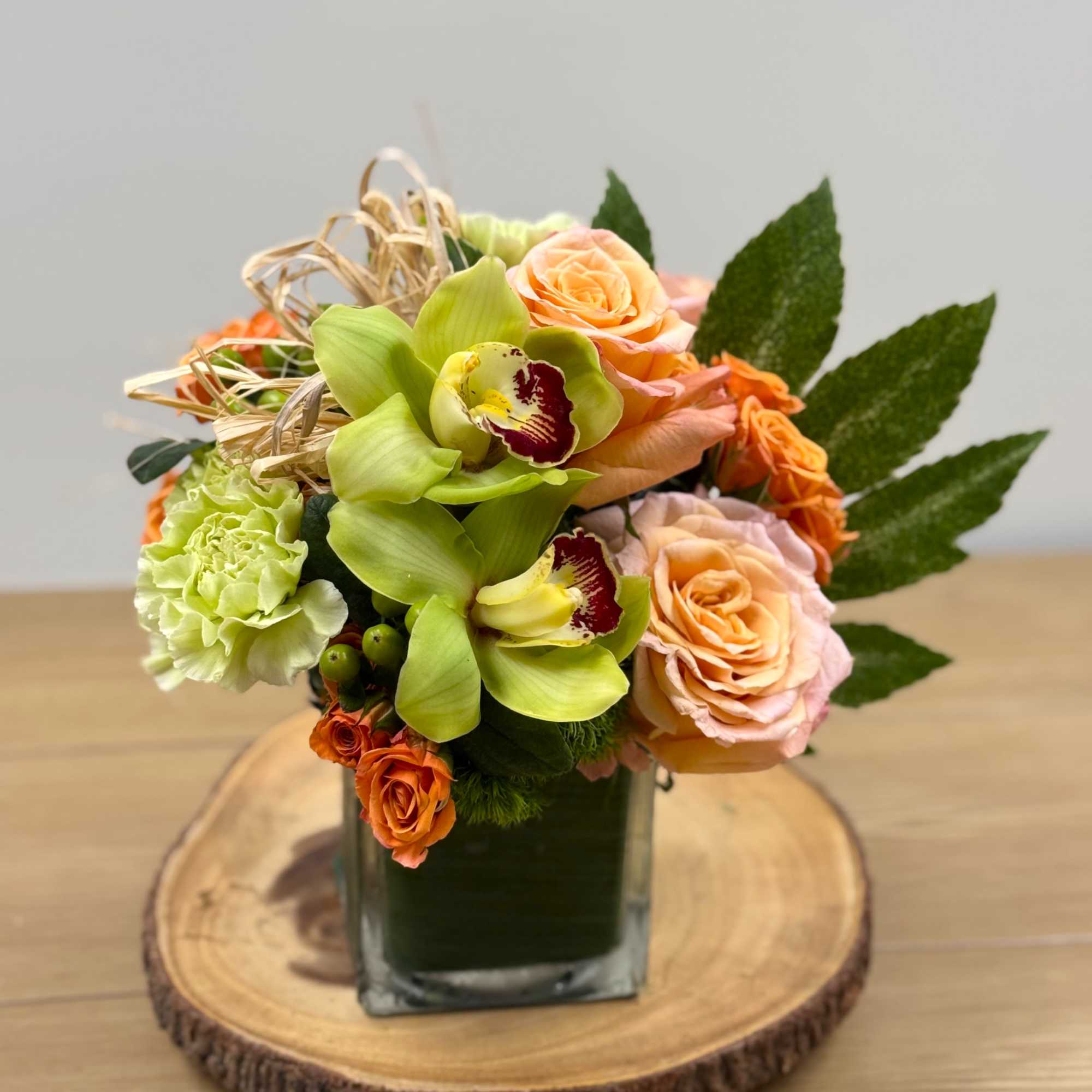 Peach and orange roses paired with vivid green orchids give this Summer