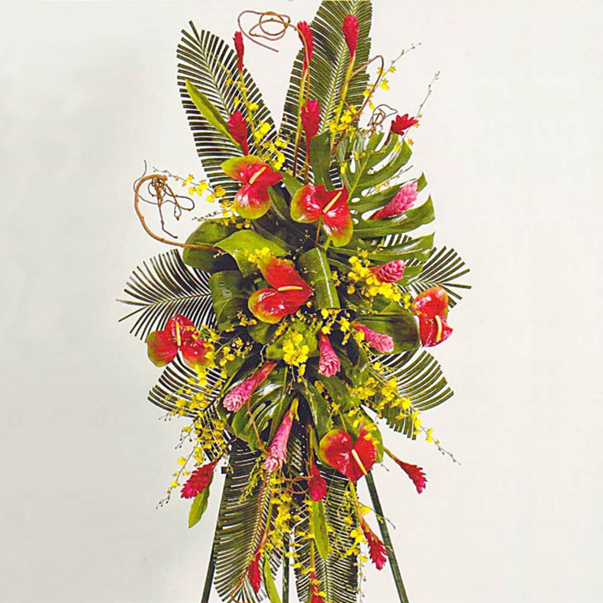 Tall tropical standing spray with red and pink blooms and yellow orchids on a green leaf backdrop