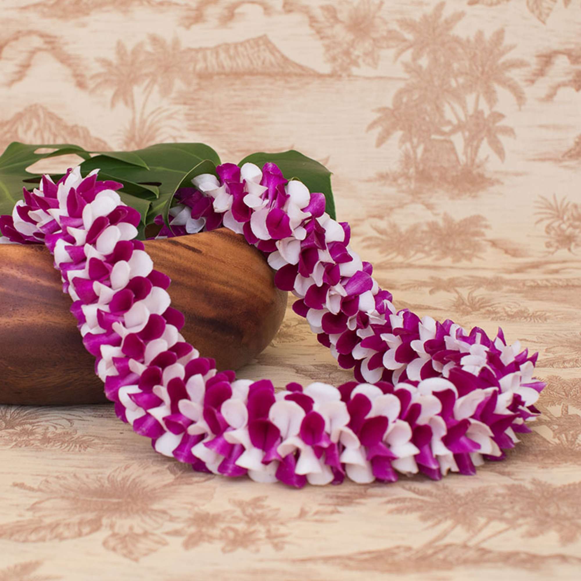 Purple and white orchid flower lei draped over a wooden bowl on a tropical background