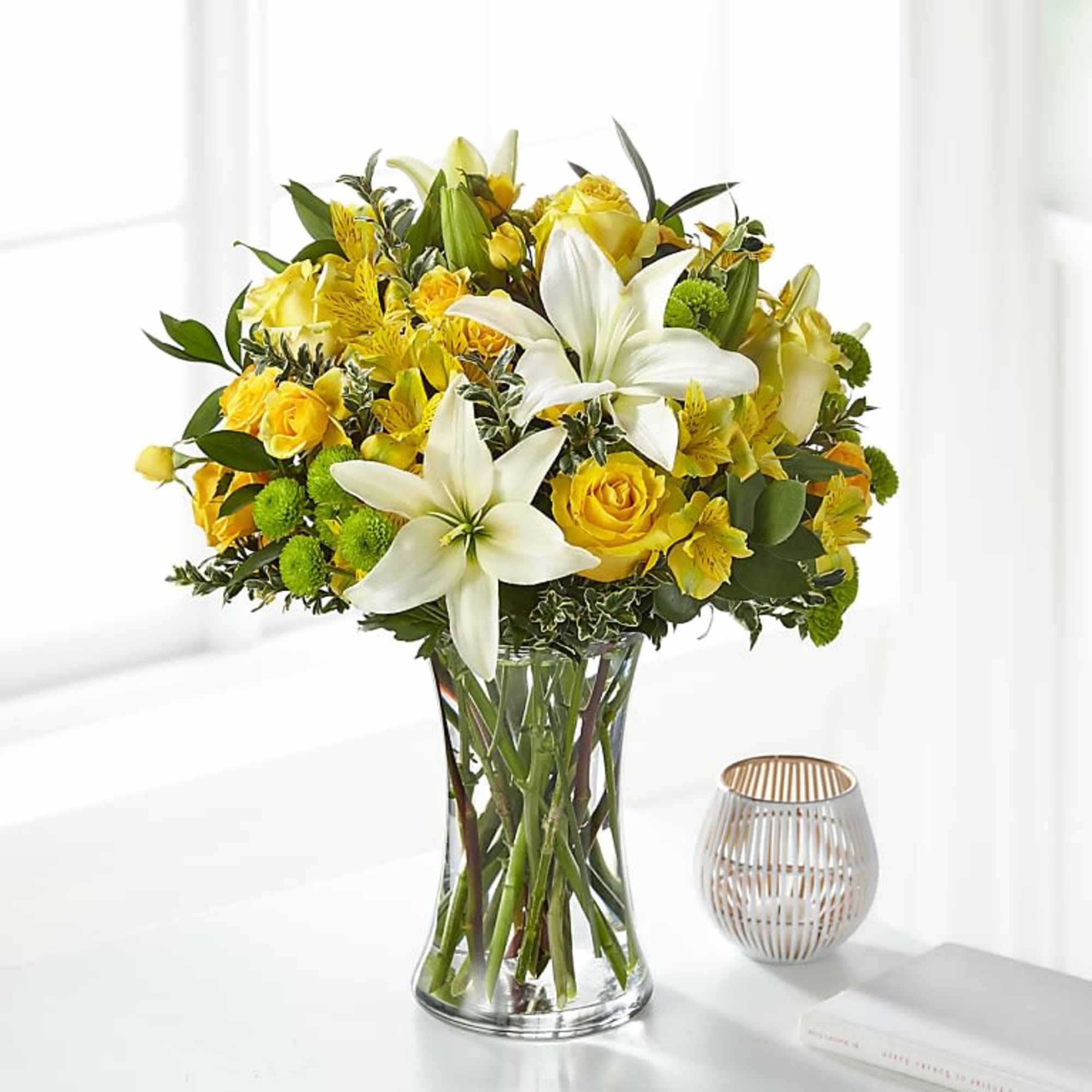 Yellow and white bouquet of lilies and roses in a clear glass vase