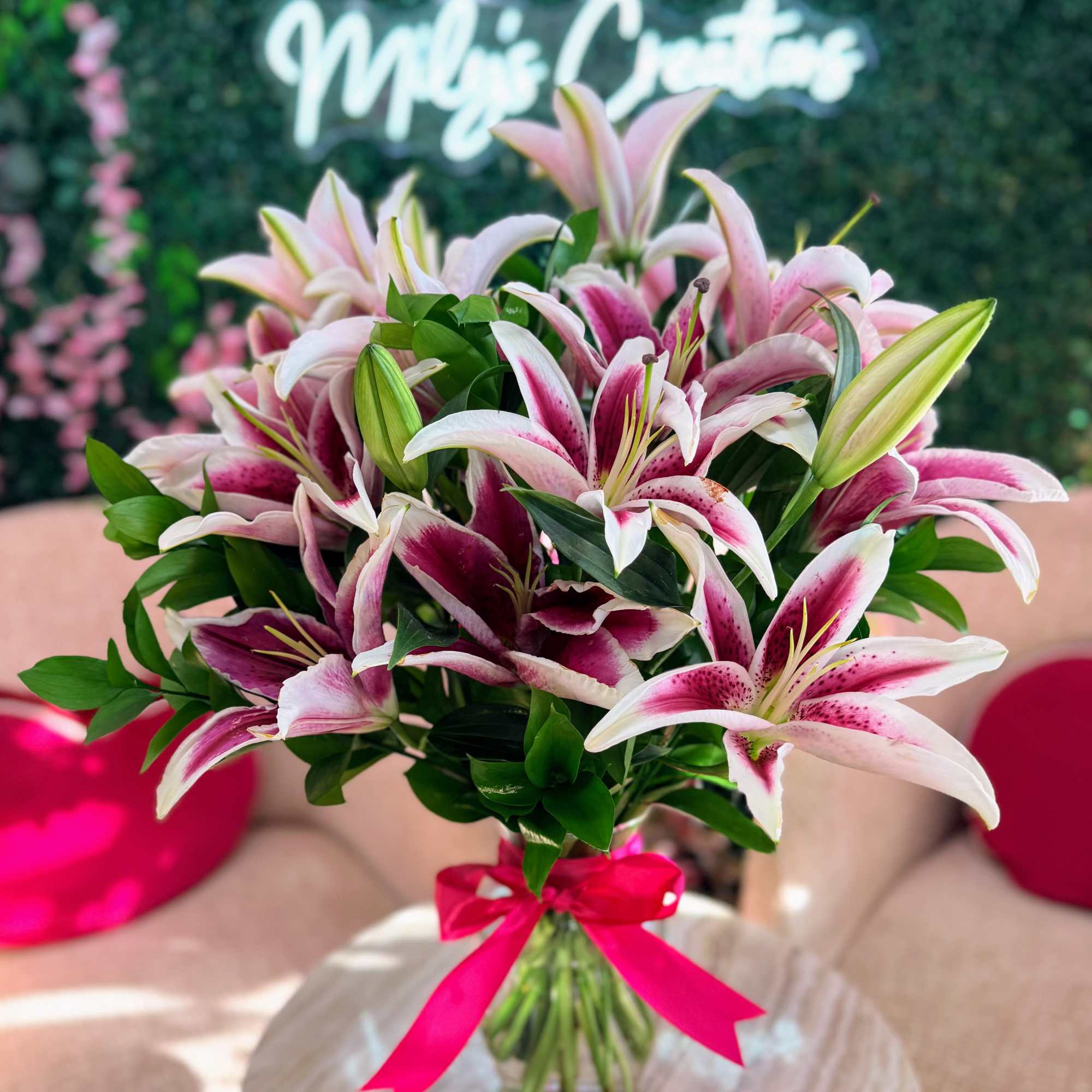 Pink and white lilies in a glass vase with a pink ribbon