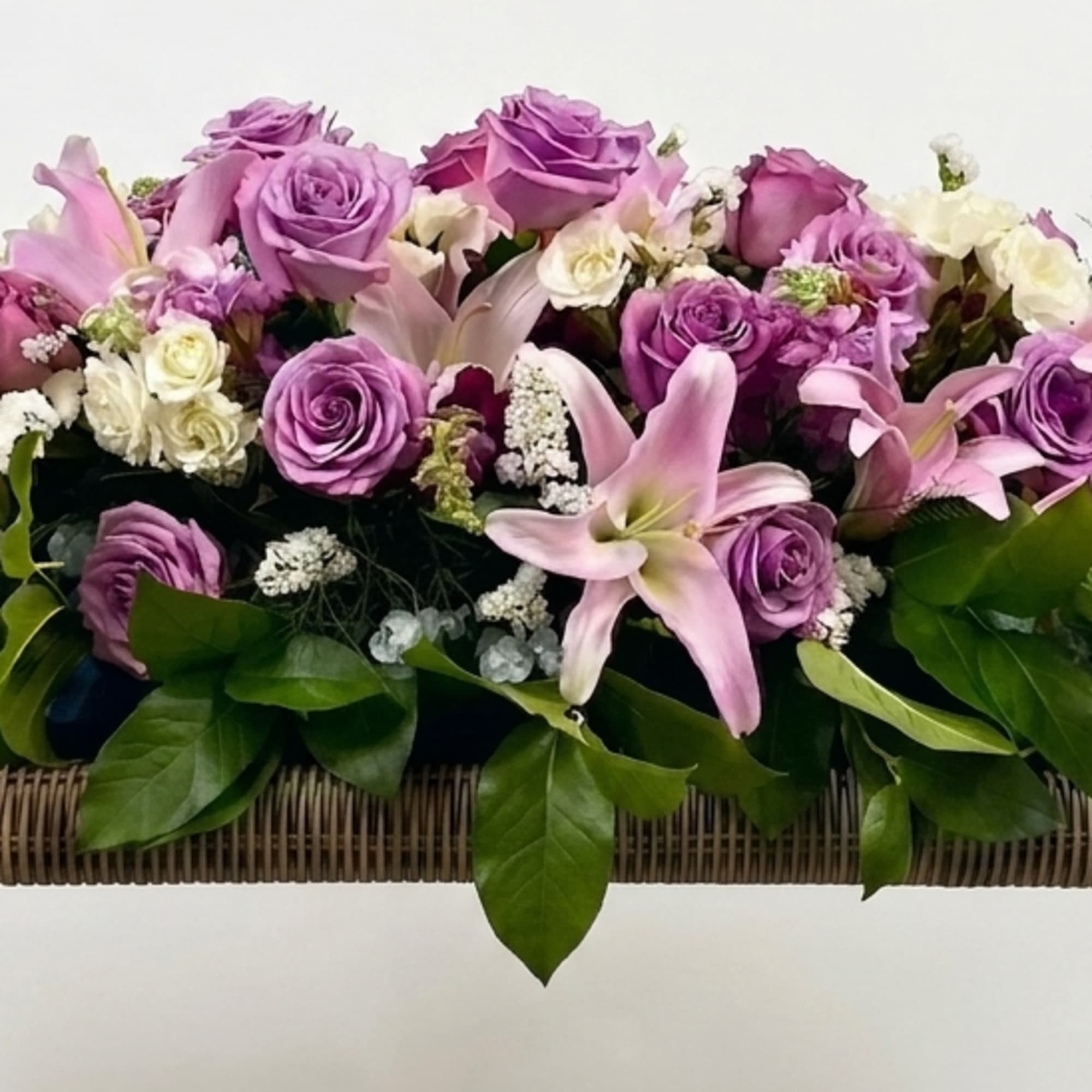 Soft lavender roses and pale pink lilies spill across a low, elongated