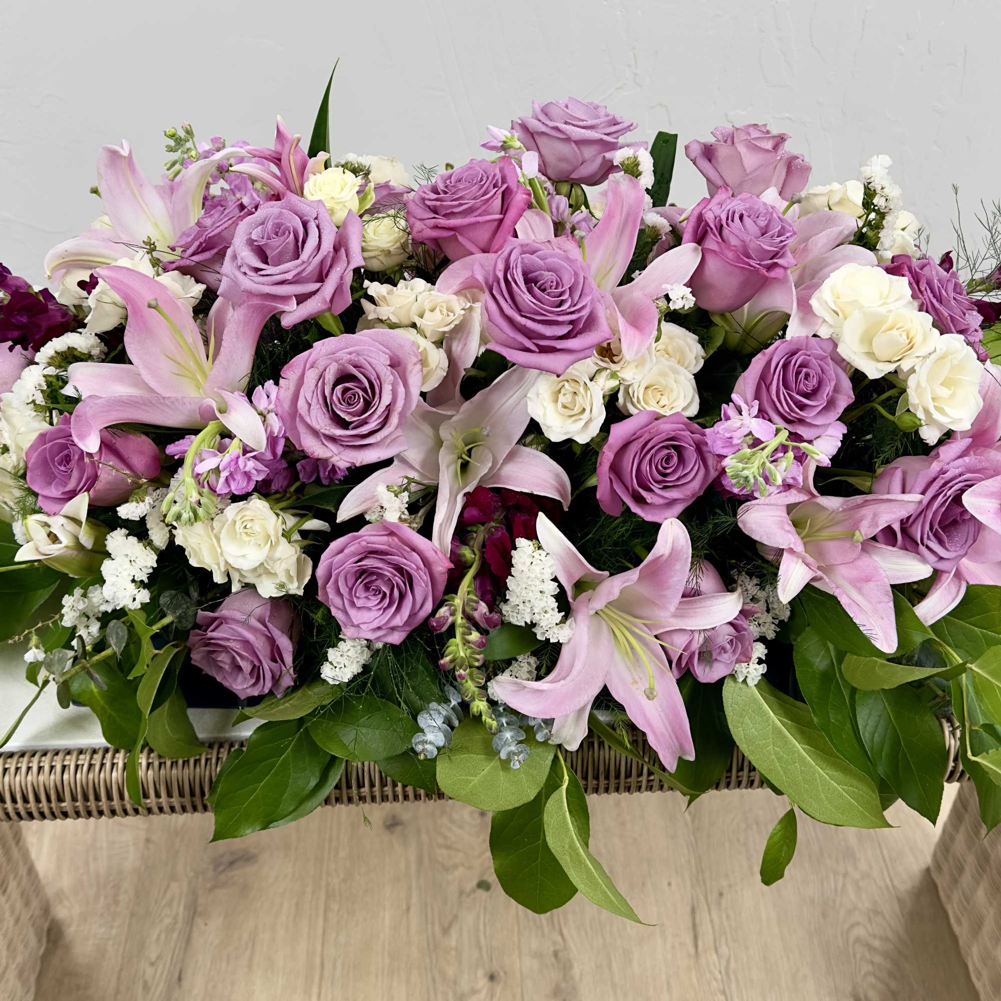 Soft lavender roses and pale pink lilies spill across a low, elongated