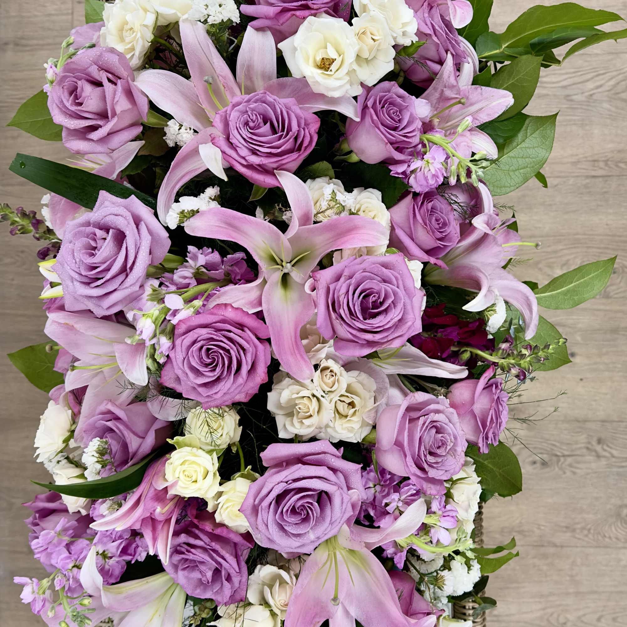 Soft lavender roses and pale pink lilies spill across a low, elongated