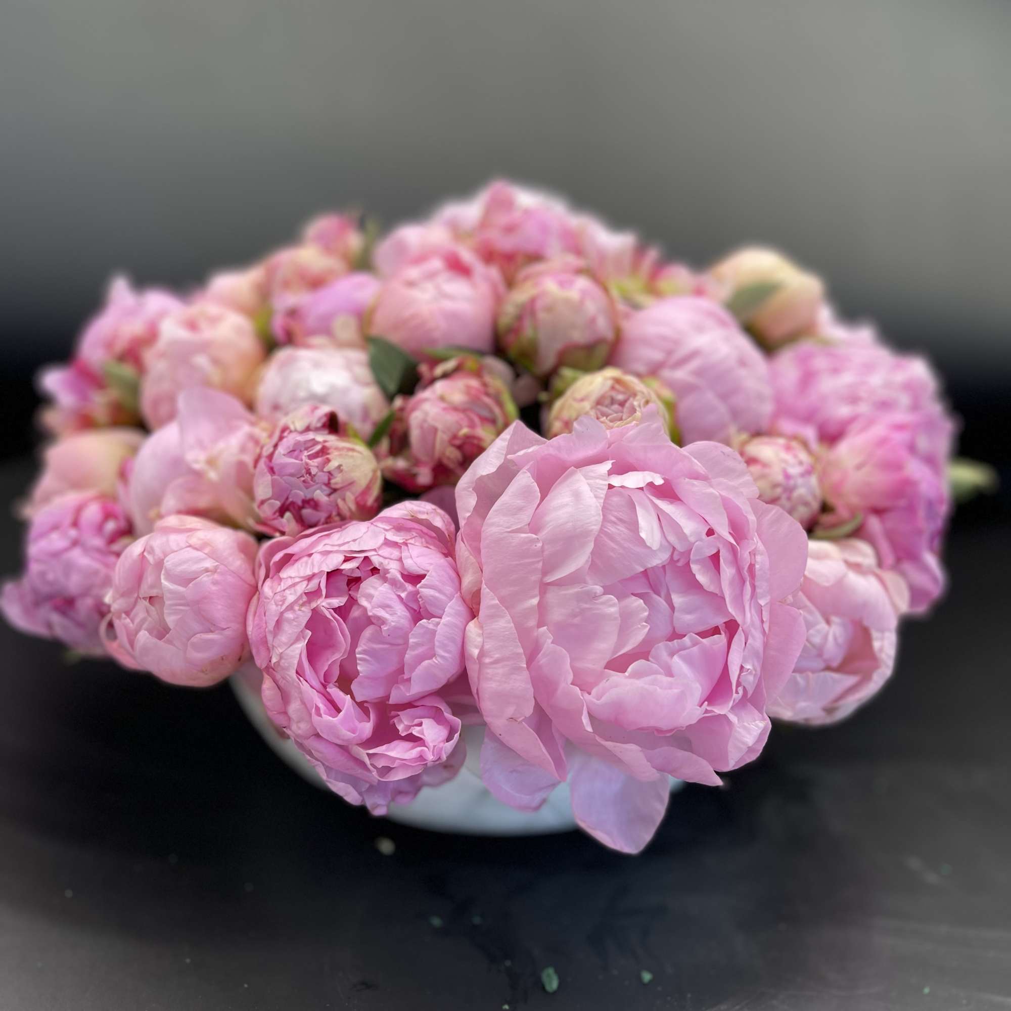 Pink peony bouquet in a low white bowl
