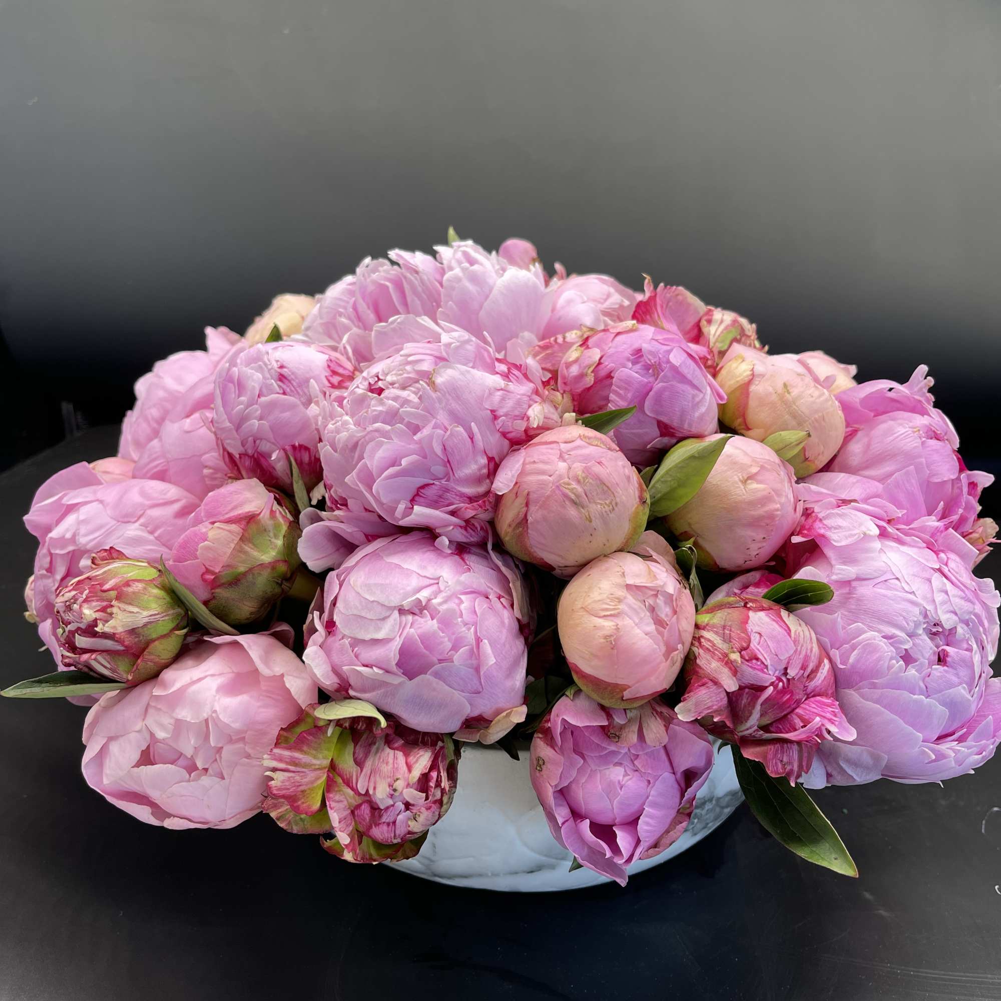 Pink peony bouquet in a white bowl vase