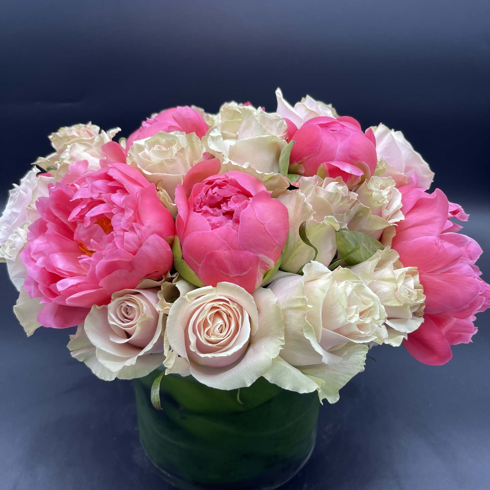 Pink peonies and pale roses arranged in a green vase