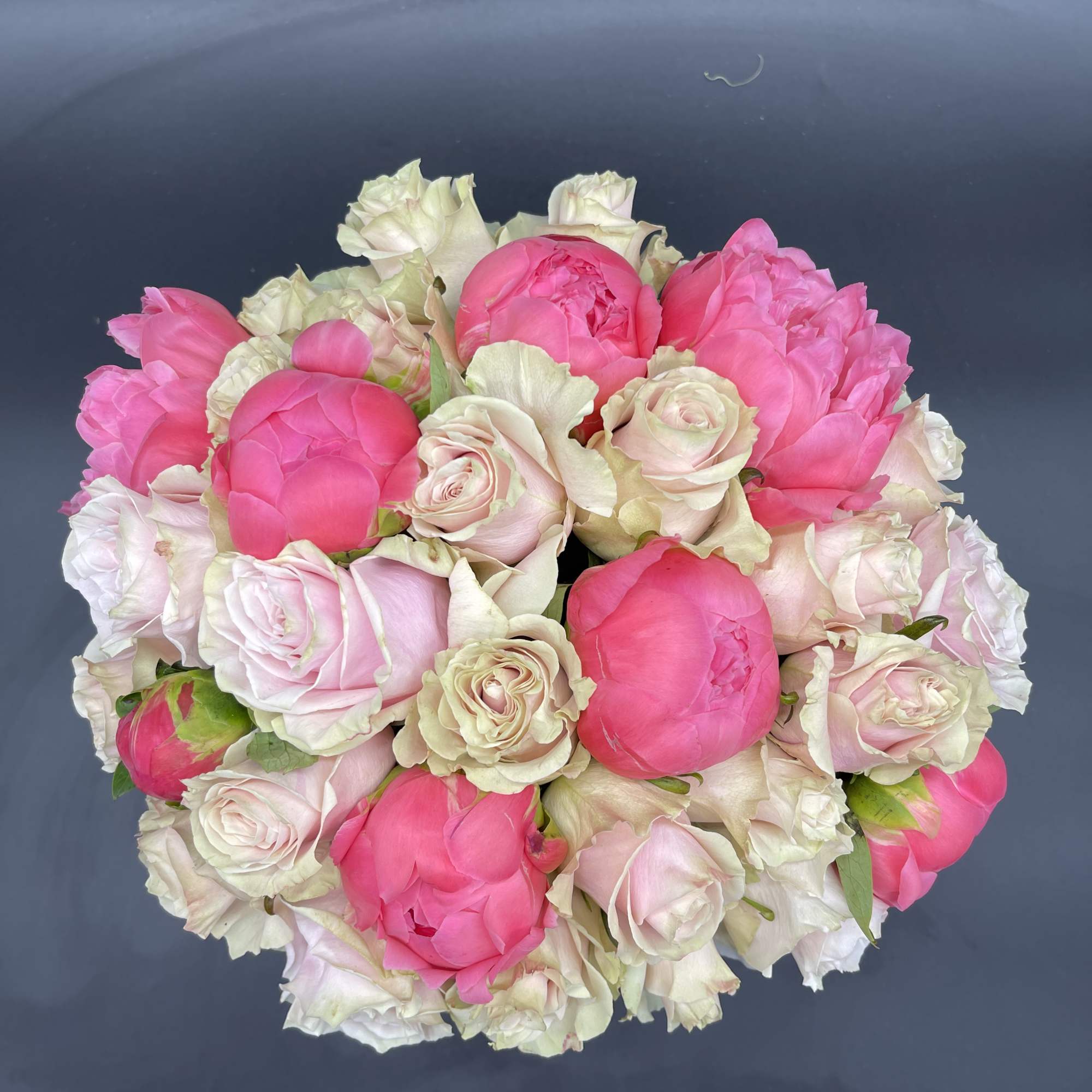 Round bouquet of pink and white roses on a dark surface