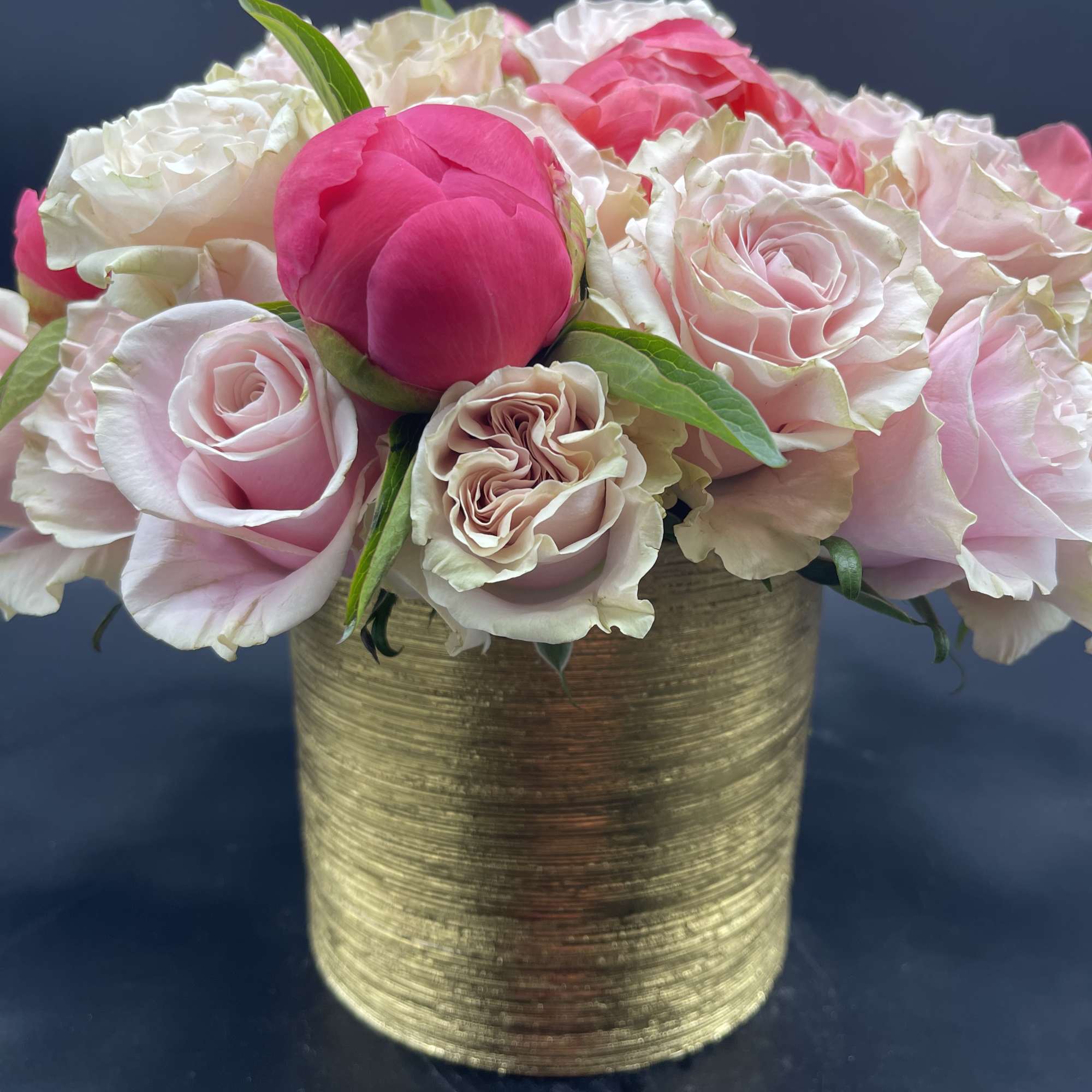Pink and white roses arranged in a gold vase