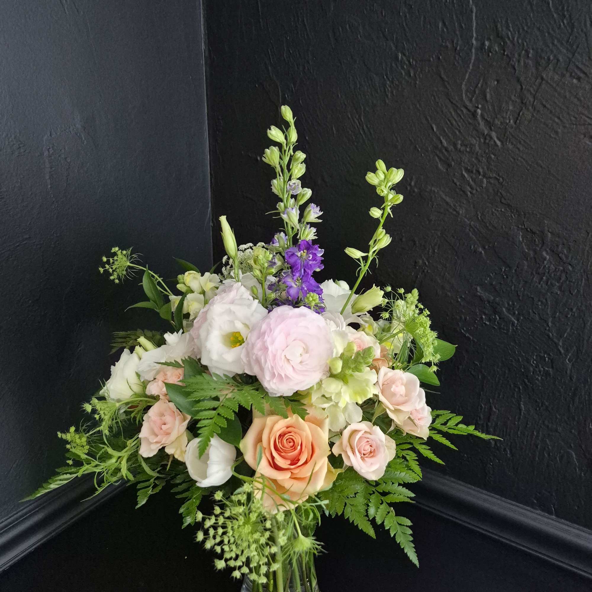 Soft blush roses and tall lavender delphinium create a gentle, garden-fresh statement, photo 2 of 2