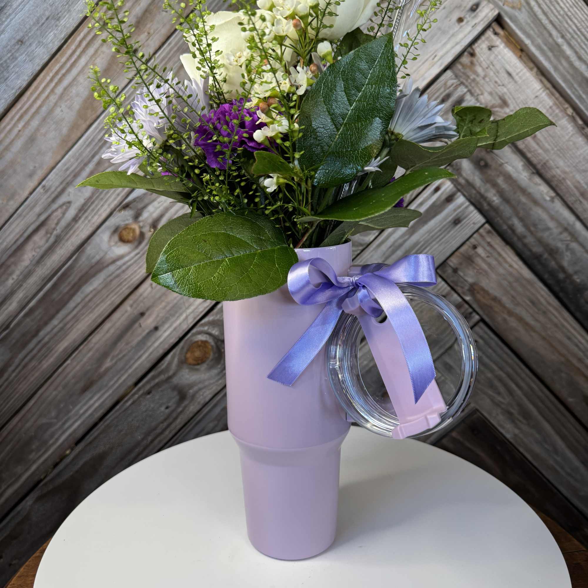White and purple bouquet in a lavender tumbler with a ribbon