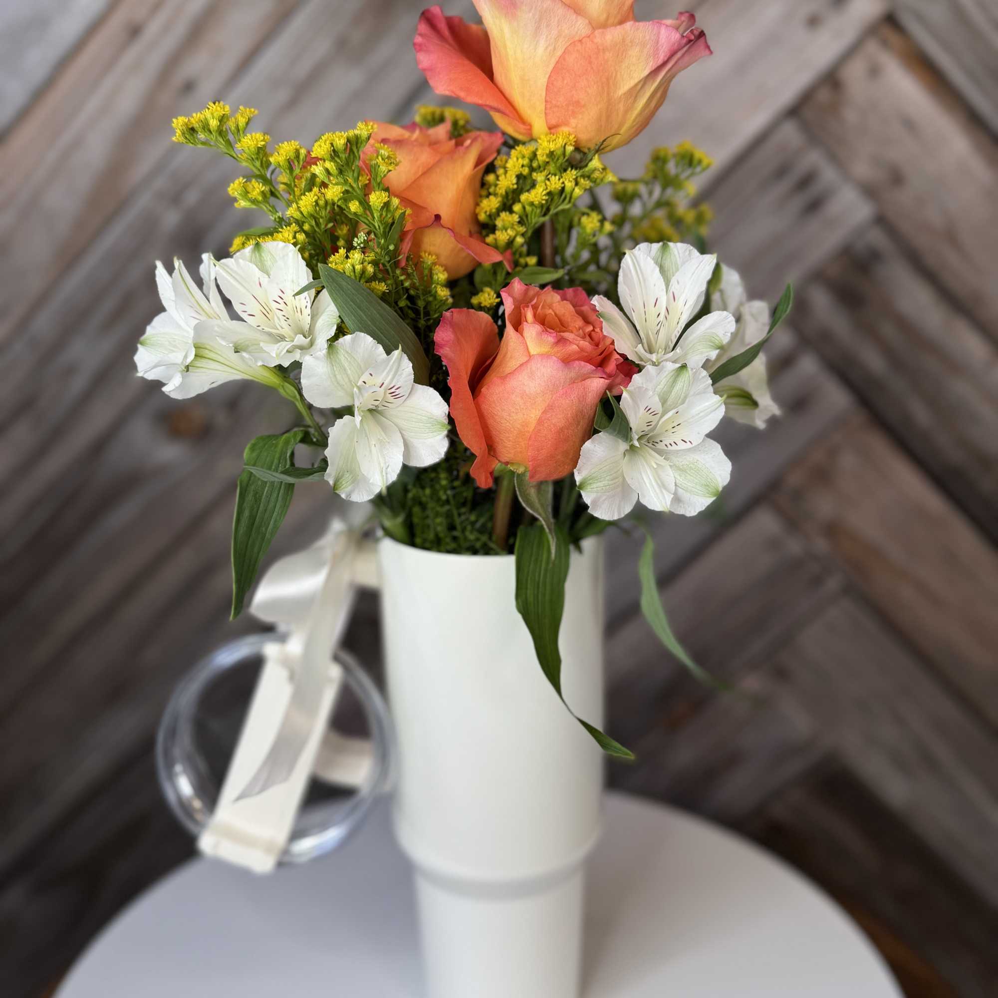 Orange roses and white alstroemeria in a white vase