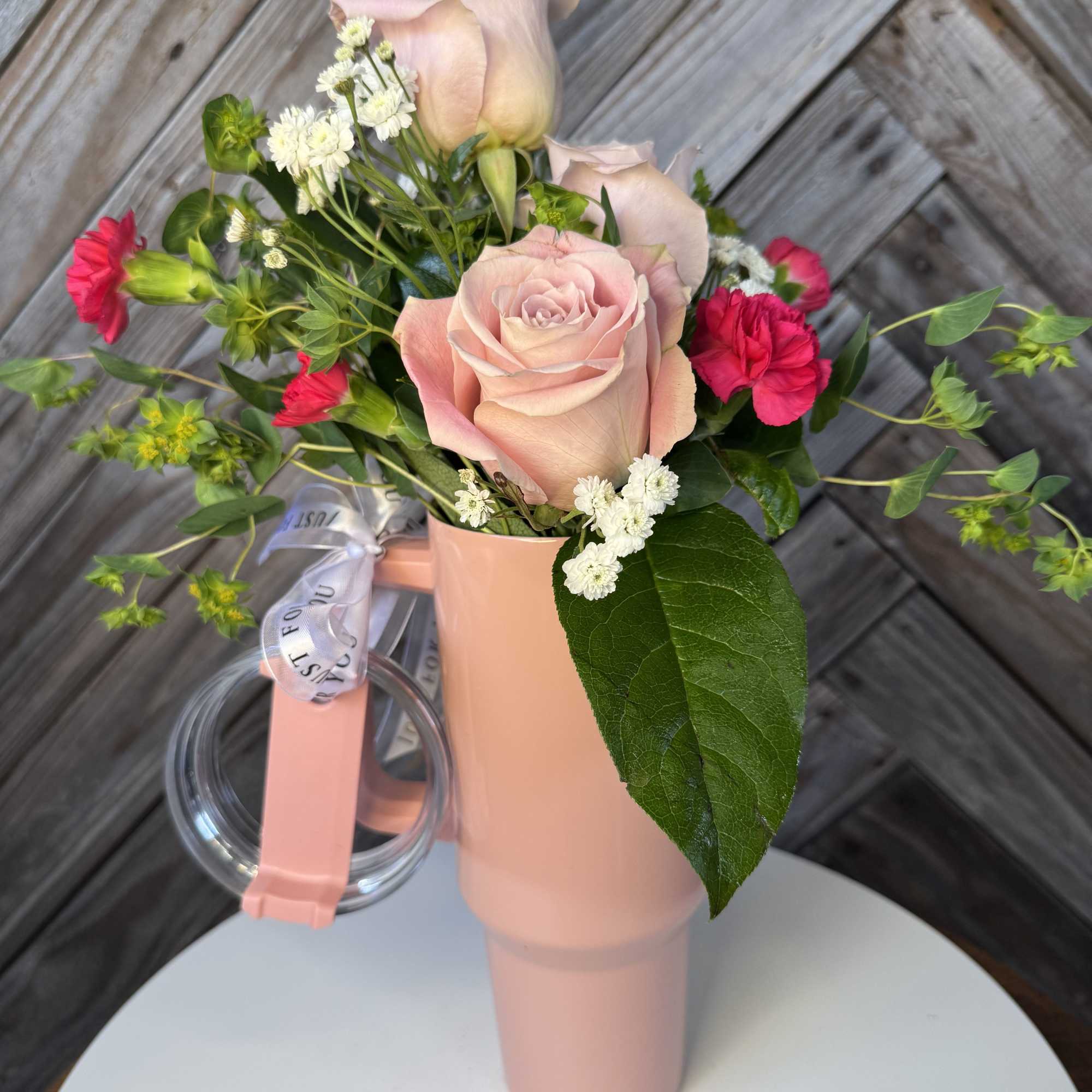 Pink roses and red carnations in a blush vase with a ribbon