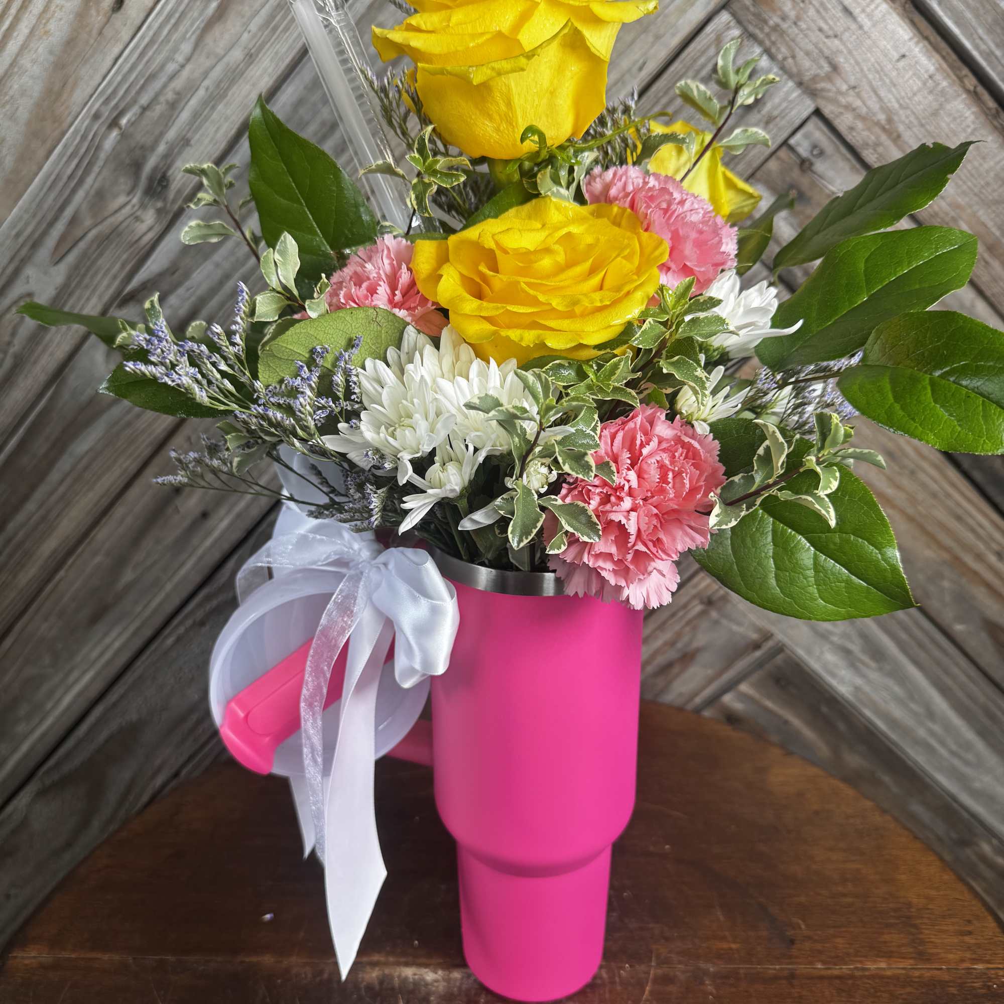 Yellow roses and pink carnations in a bright pink mug-shaped vase