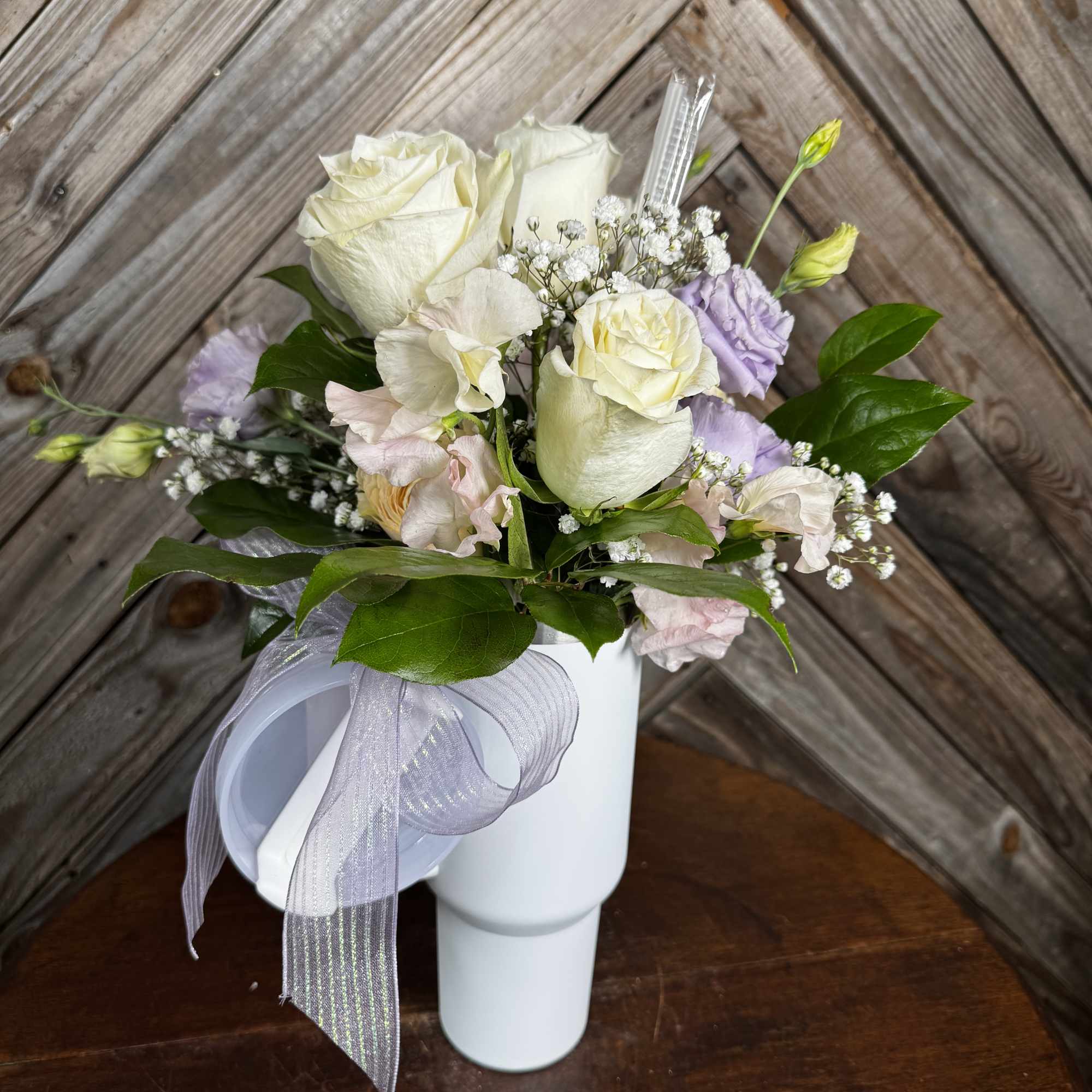 White and pale lavender bouquet in a white vase with a ribbon