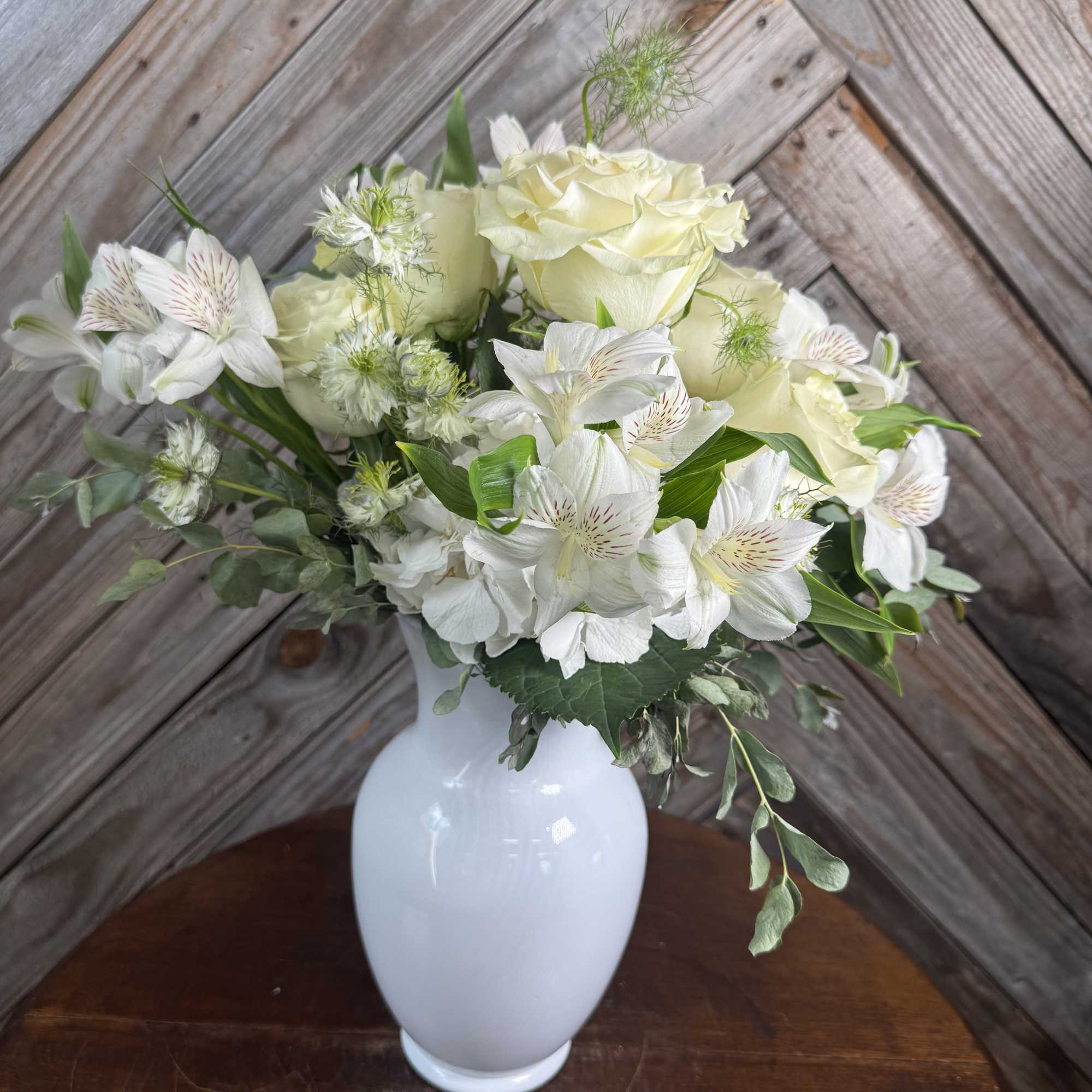 White roses and alstroemeria arranged in a white vase