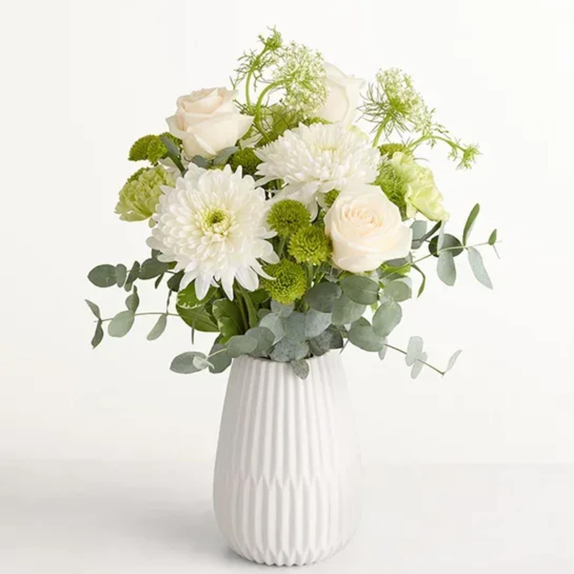 Soft white roses and full chrysanthemum blooms mingle with pale green button