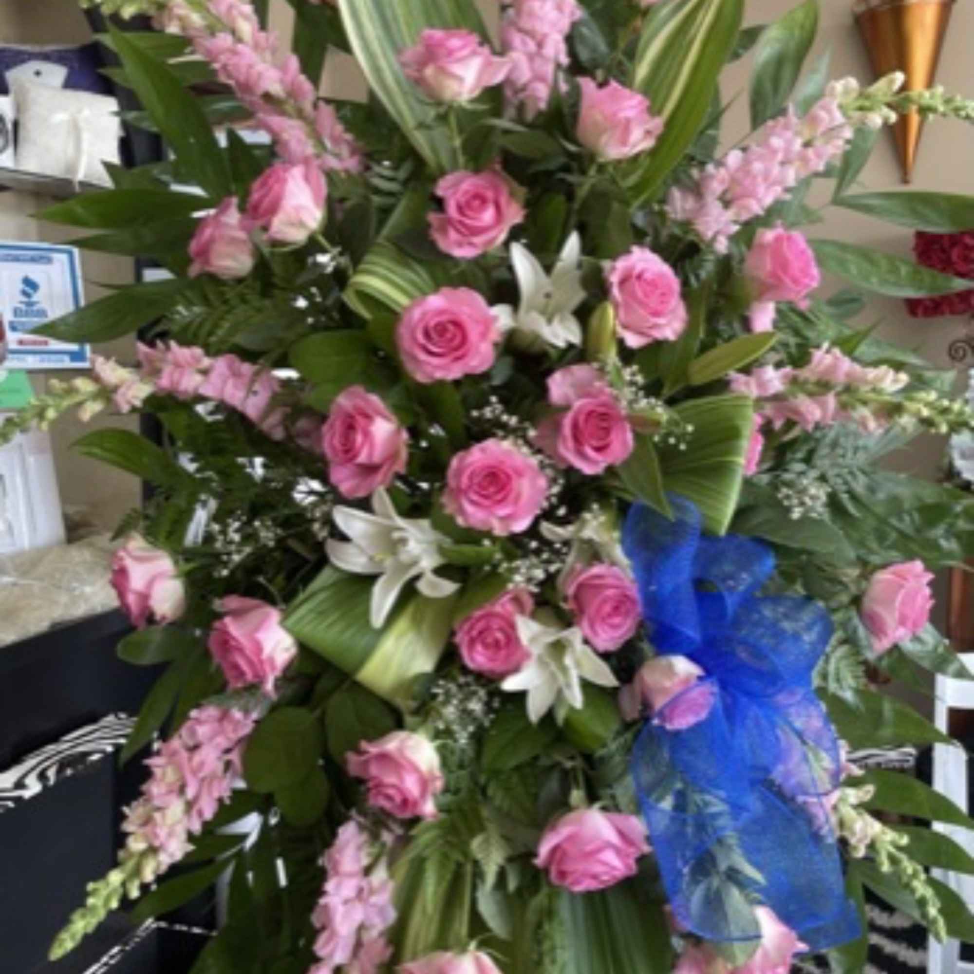 Tall pink rose arrangement with white lilies and a blue ribbon