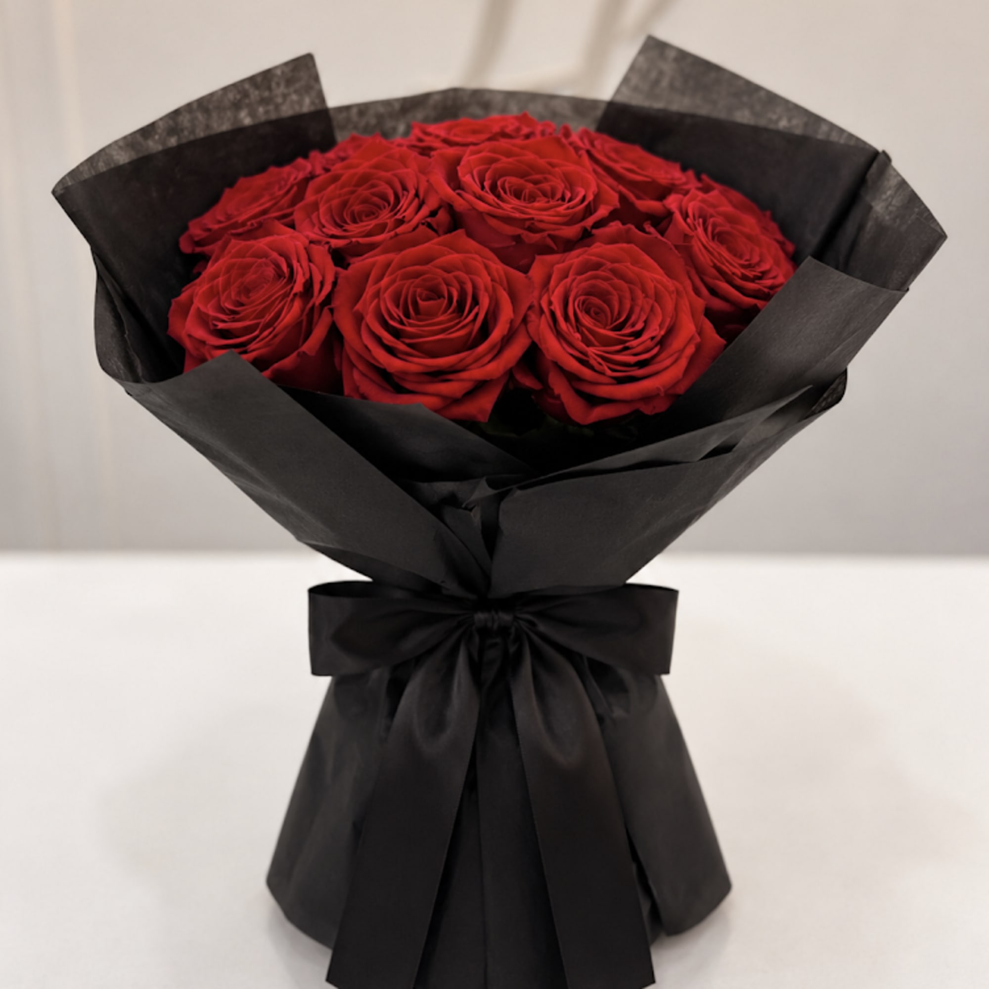 Bouquet of red roses wrapped in black paper with a black ribbon