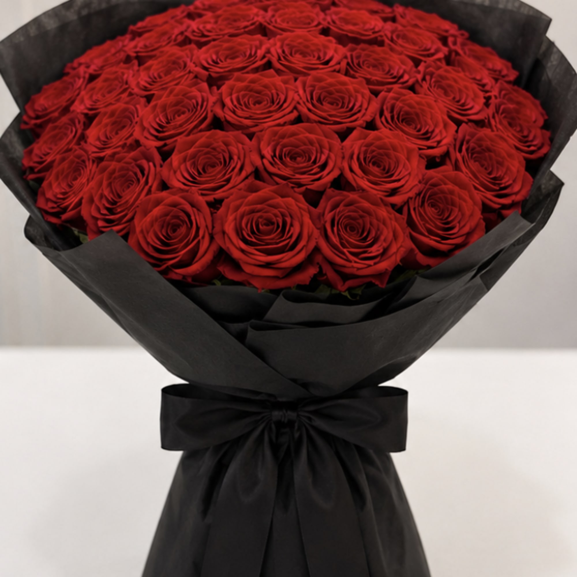 Large bouquet of red roses wrapped in black paper