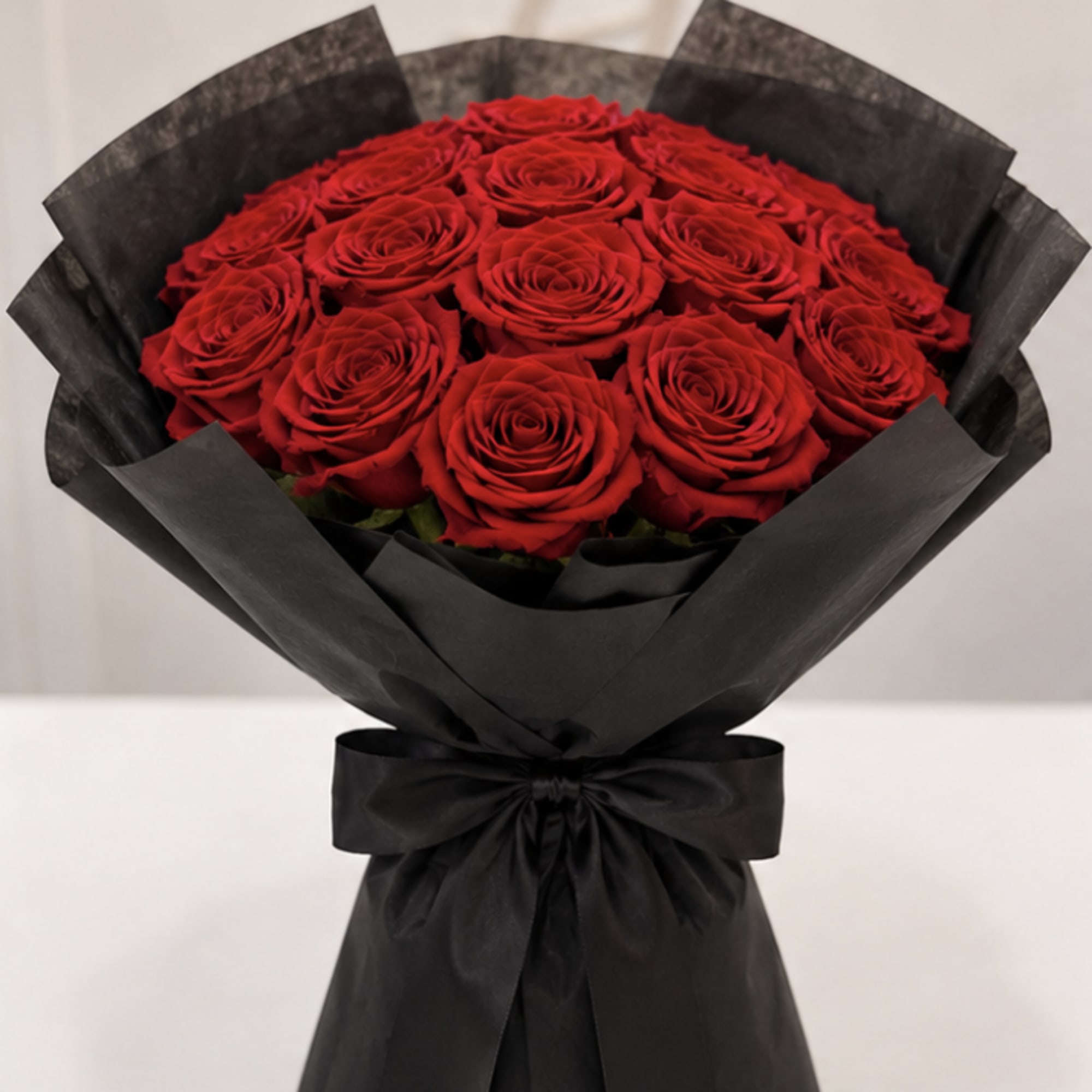 Bouquet of red roses wrapped in black paper with a black ribbon