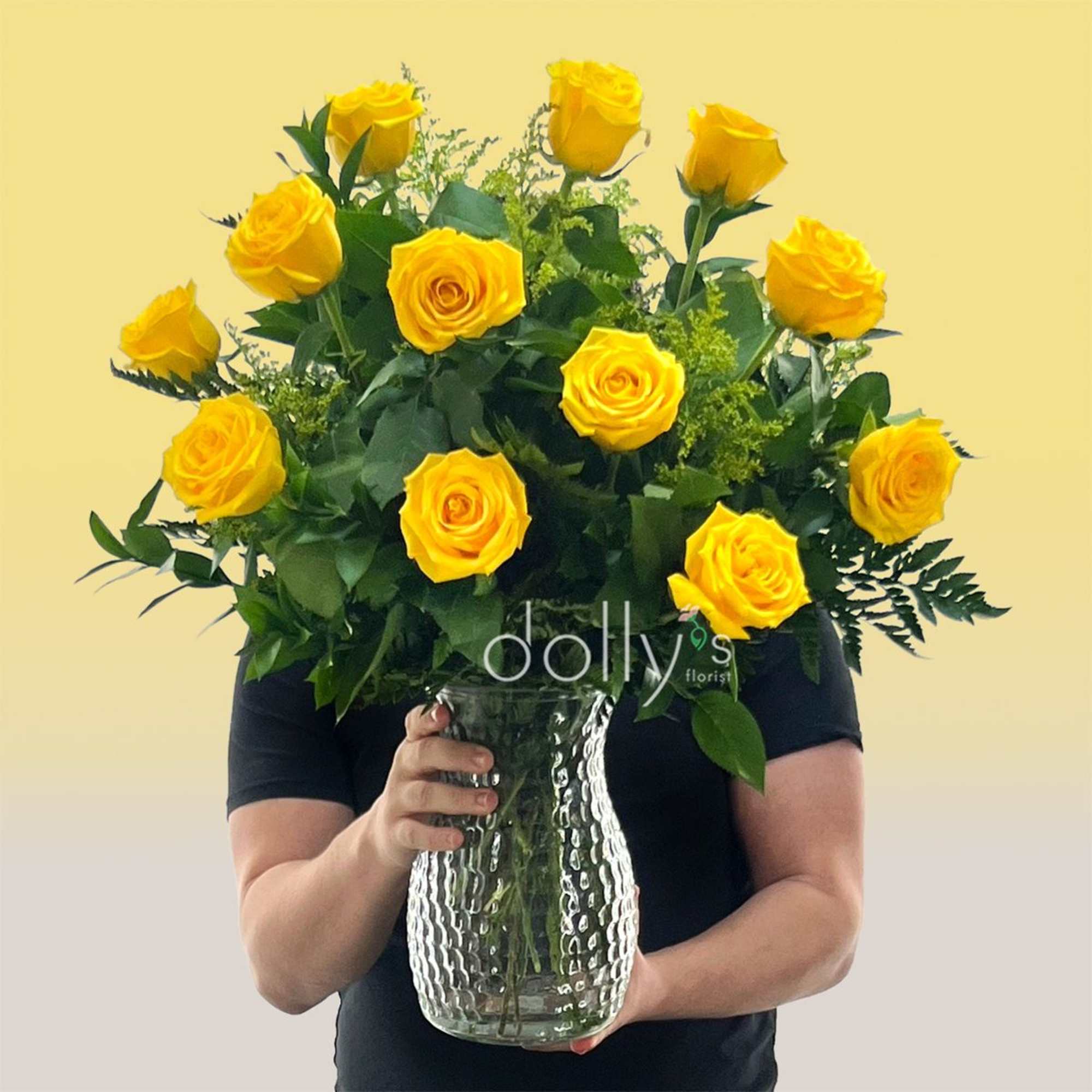 A cluster of bright yellow roses arranged in a clear glass vase