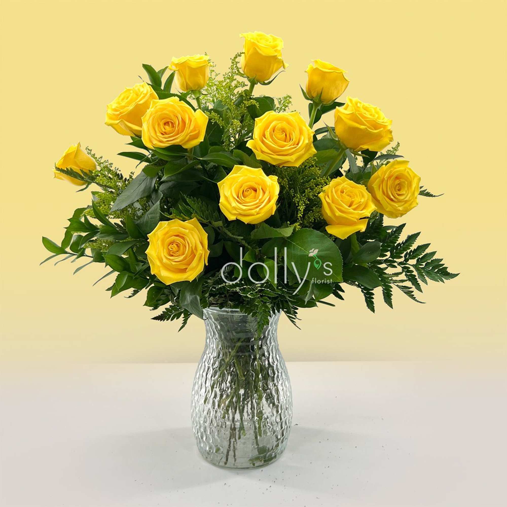 A cluster of bright yellow roses arranged in a clear glass vase
