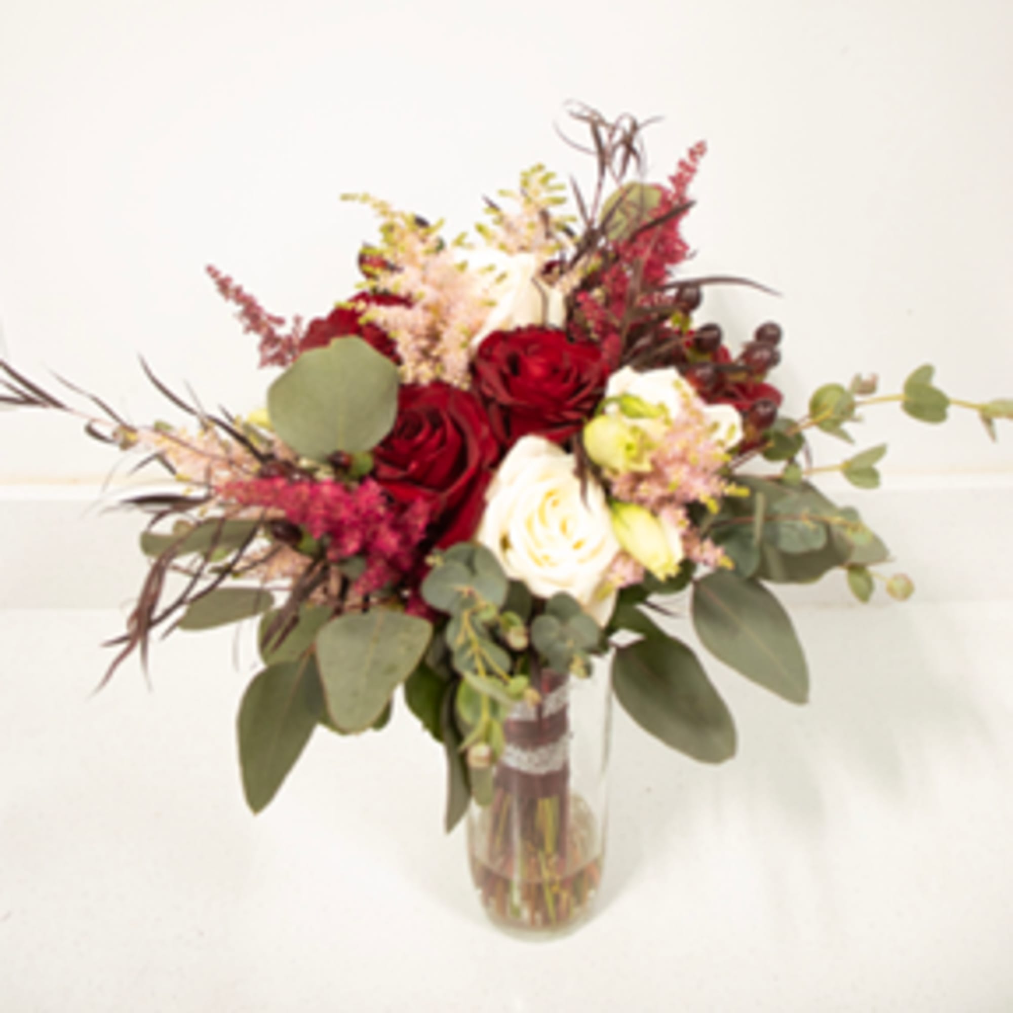 Red and white roses in a glass vase with eucalyptus