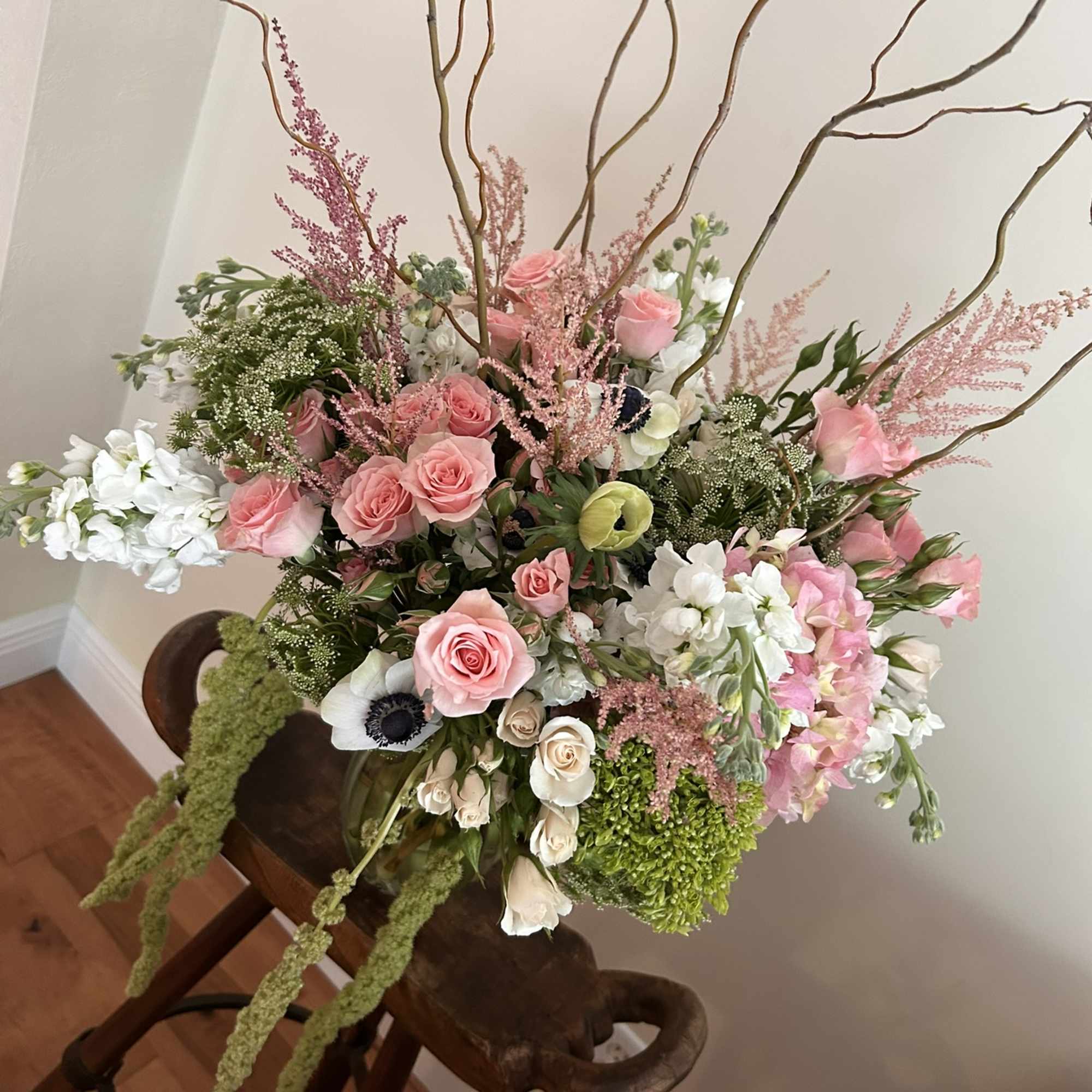 Large pink and white floral arrangement with tall branches in a vase