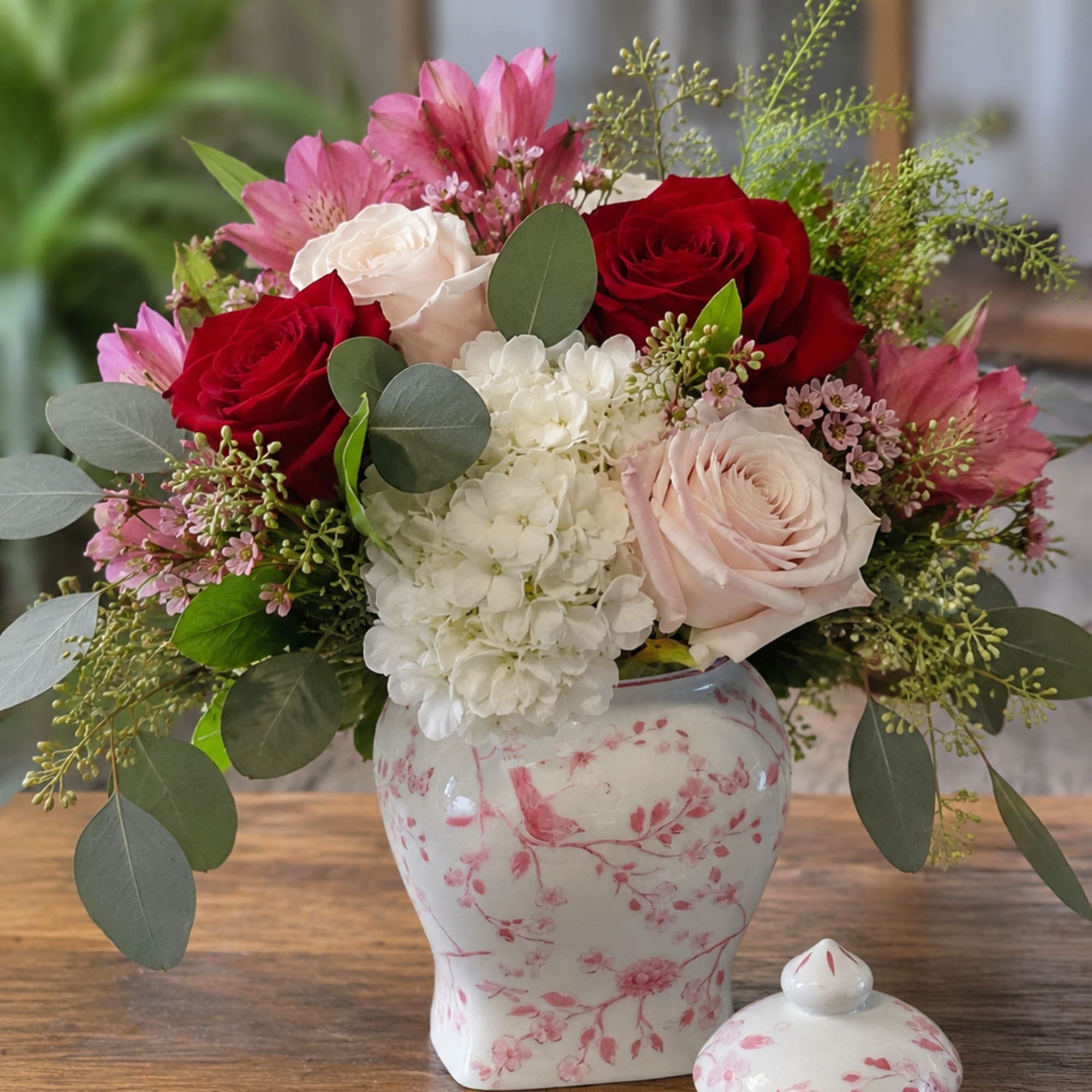 Deep red and blush roses meet a cloud of white hydrangea and