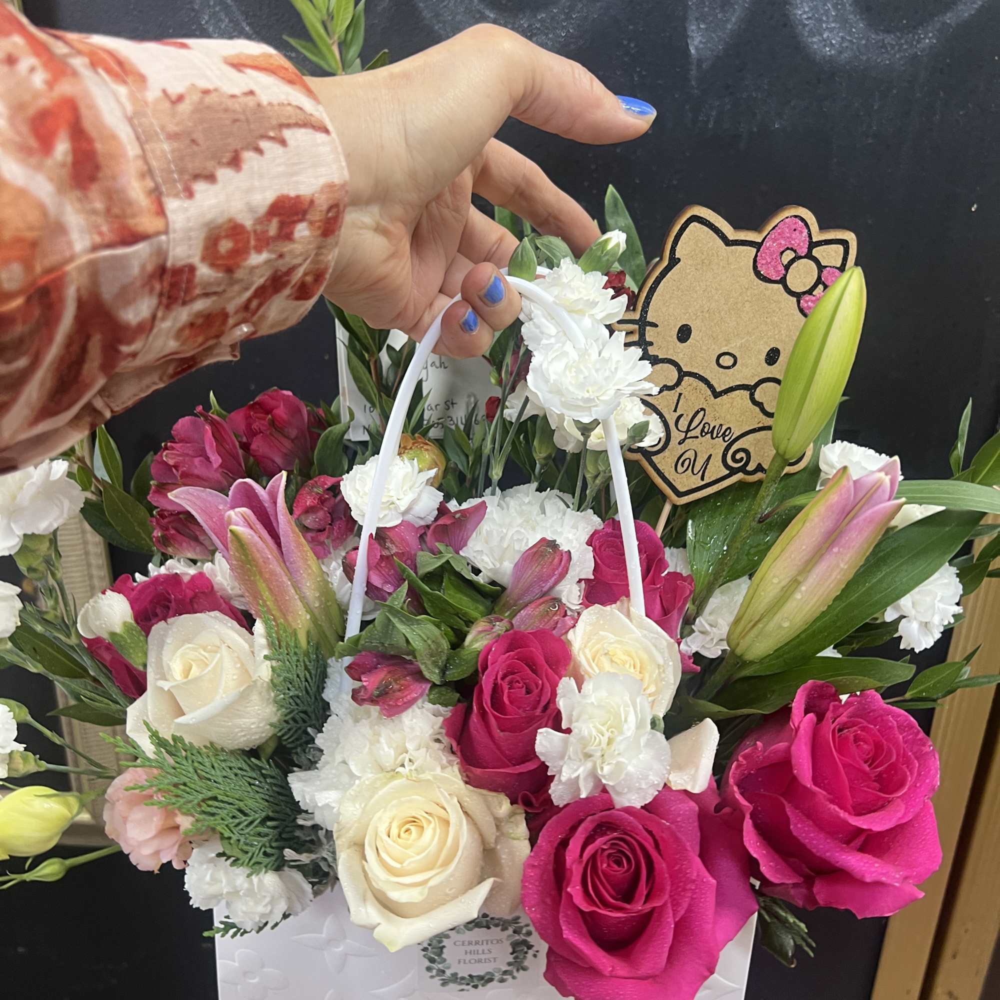Handheld flower basket with pink and white roses, lilies, and a Hello Kitty sign