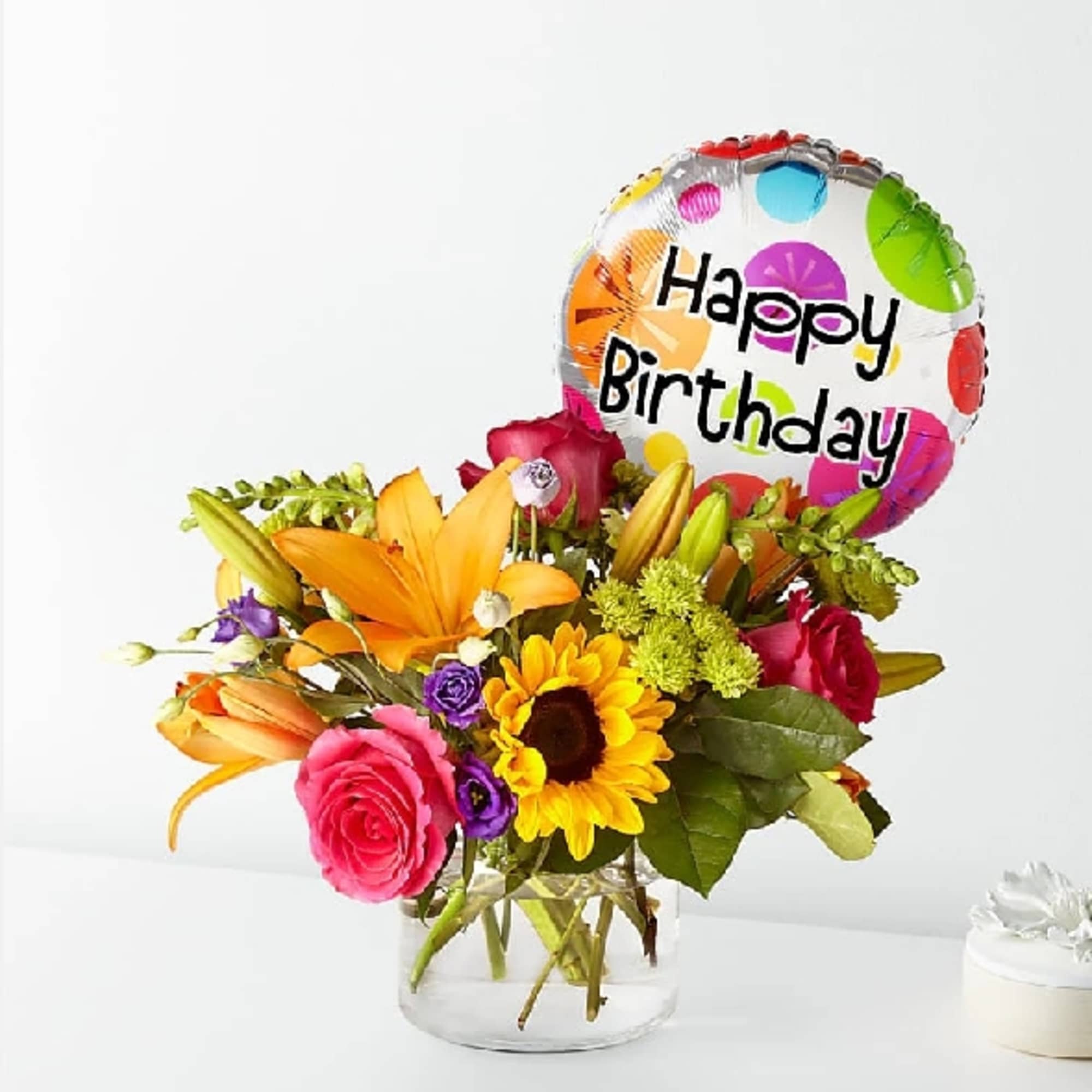 Mixed flower bouquet in a glass vase with a Happy Birthday balloon