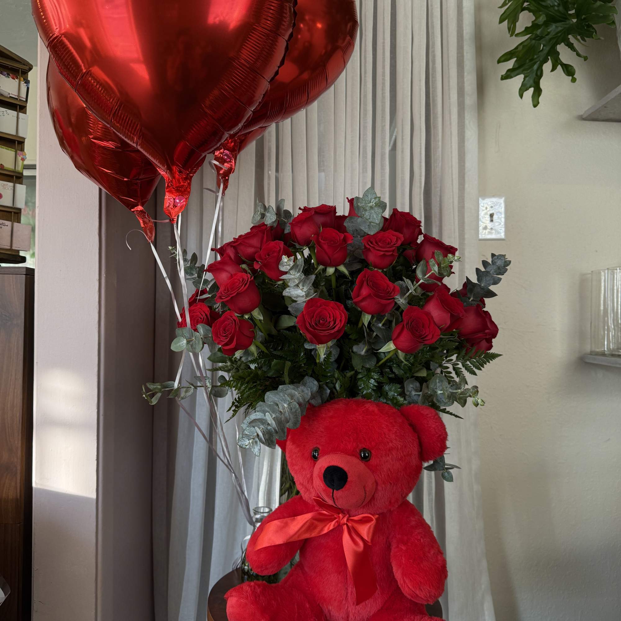 Red rose bouquet with heart balloons and a teddy bear