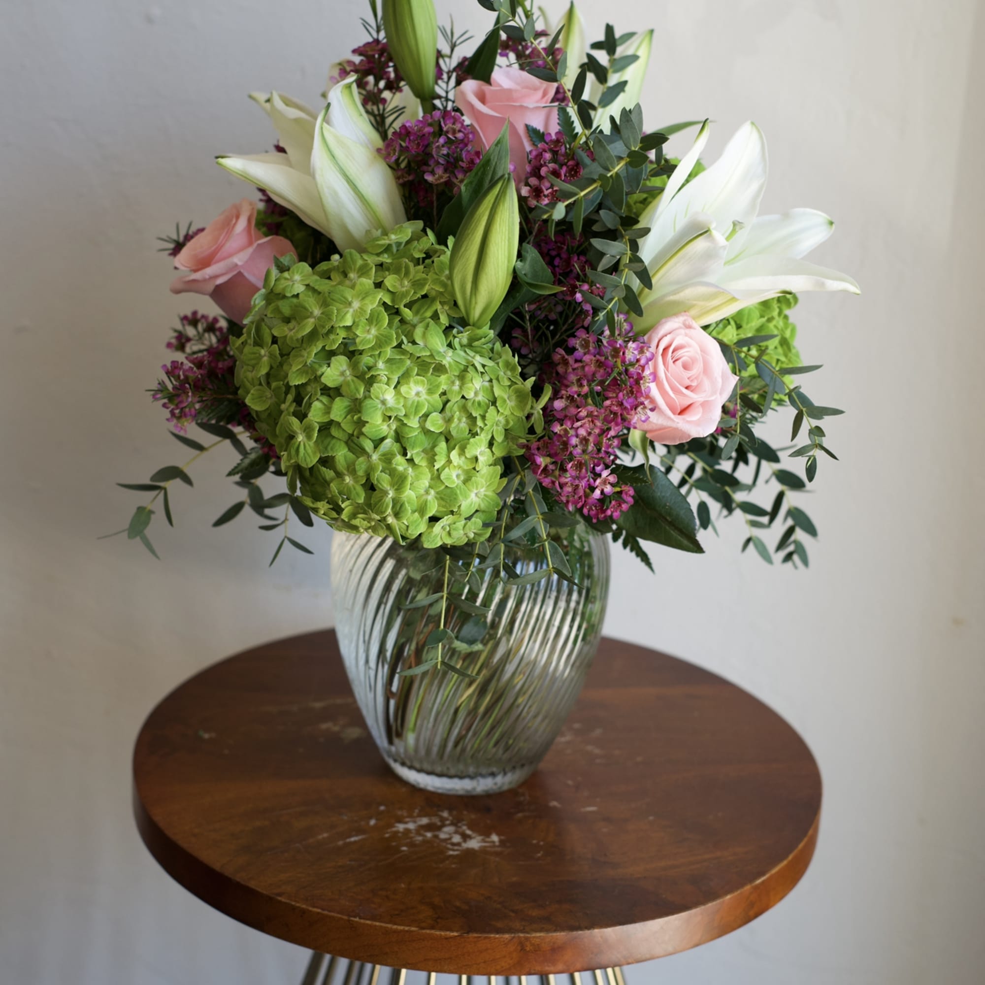 A fresh and elegant arrangement featuring lush green hydrangeas, classic roses, and
