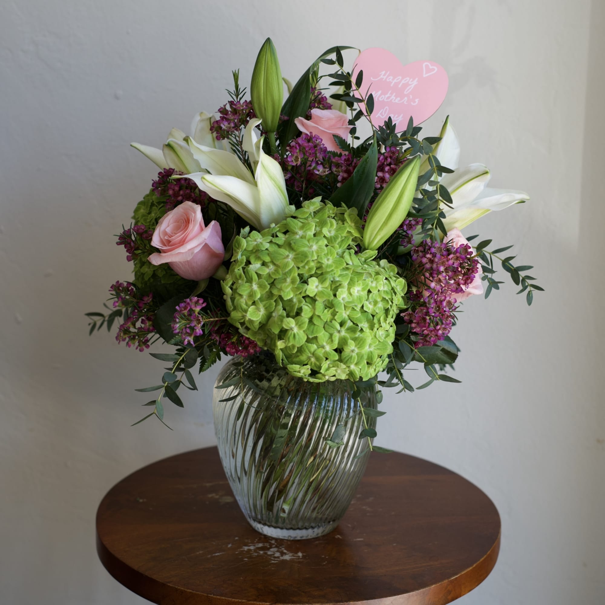 A fresh and elegant arrangement featuring lush green hydrangeas, classic roses, and