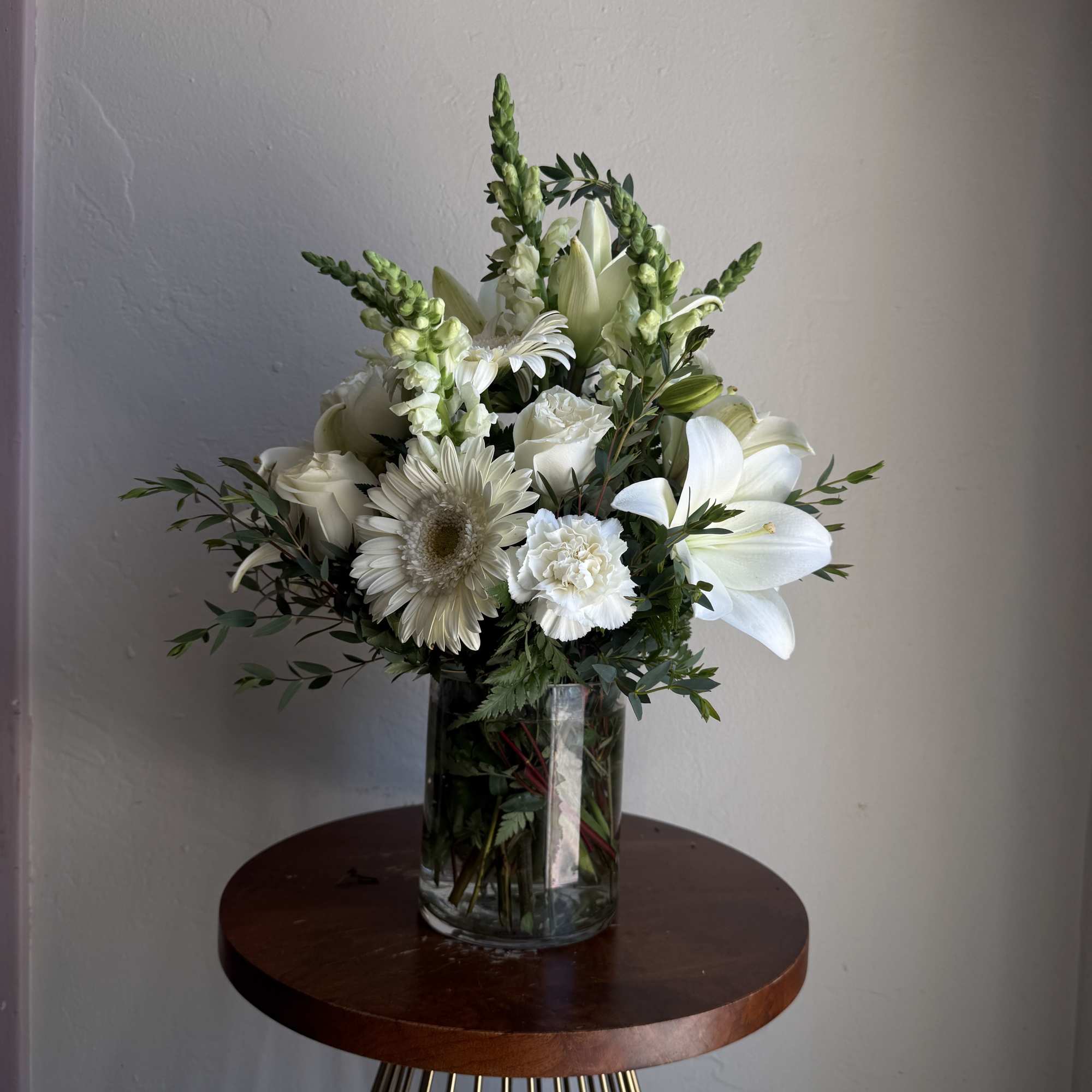 This arrangement contains gerbera daisies, roses, snapdragons and other seasonal blooms. 