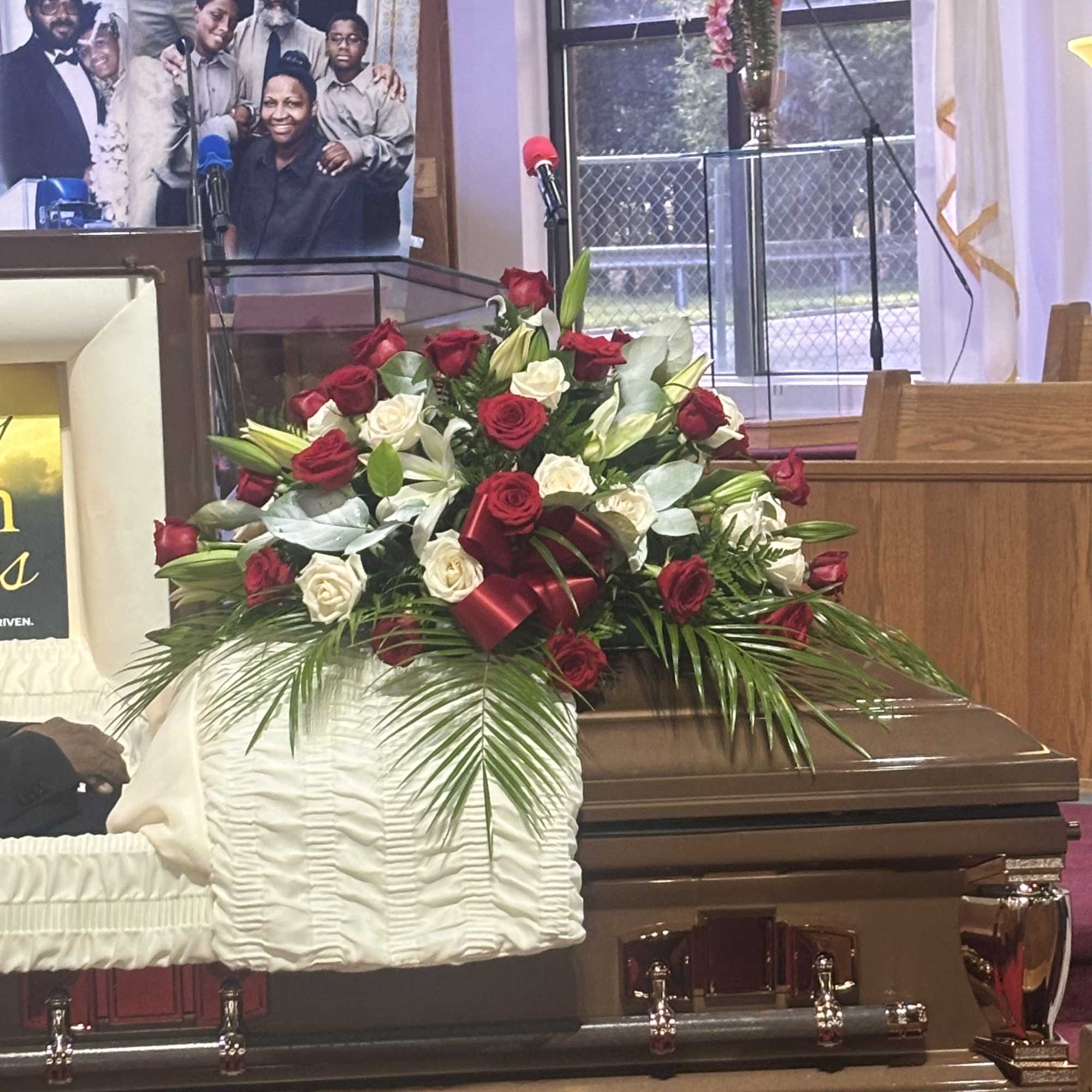 Red and white rose arrangement on a casket with palm fronds