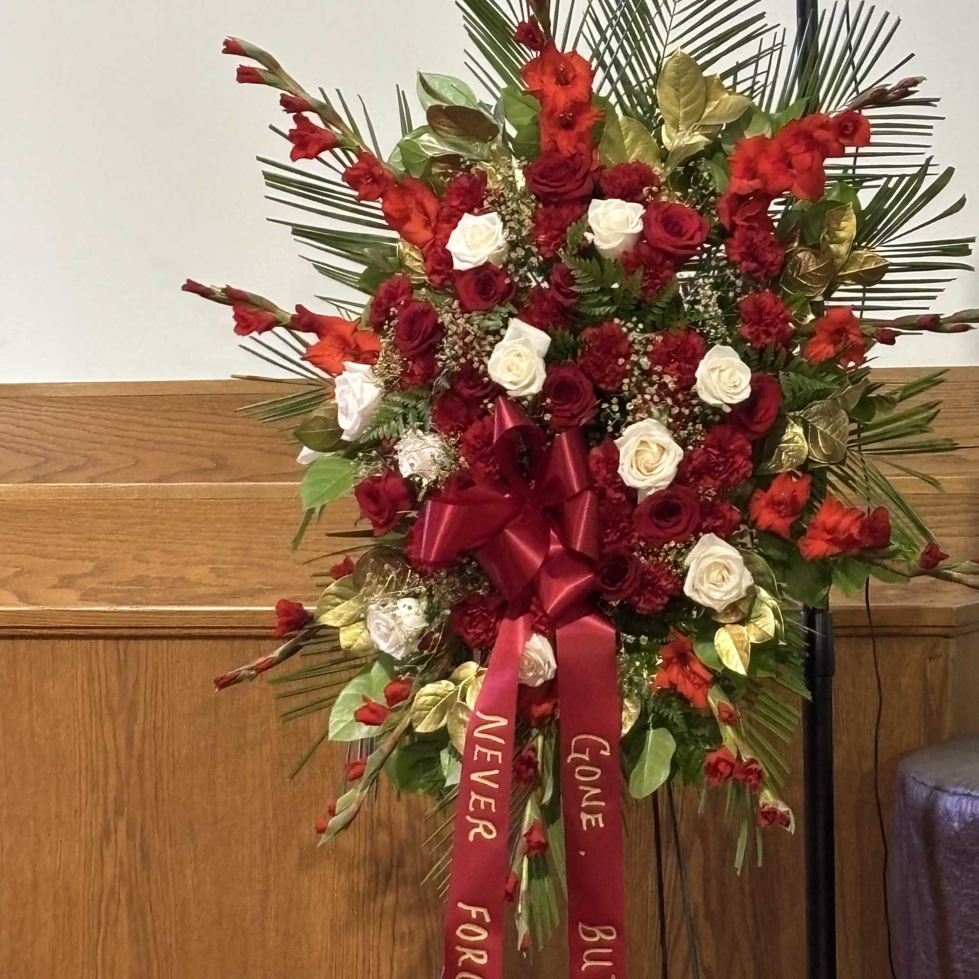 Standing floral spray with red and white roses and red ribbons