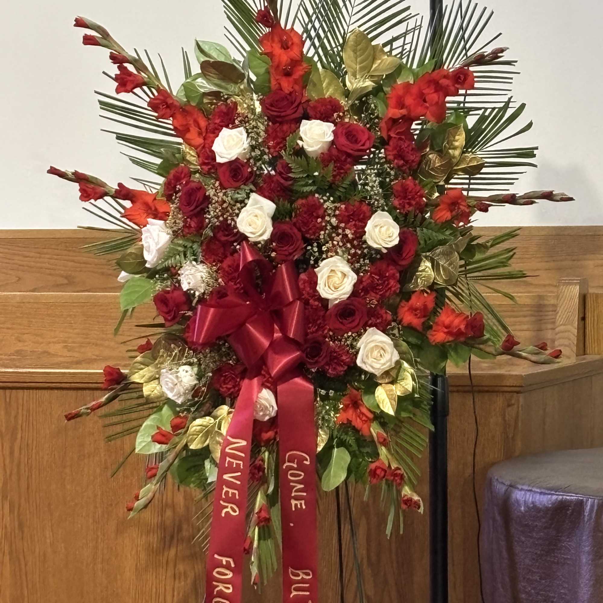 Standing red and white floral spray with ribbon streamers on an easel