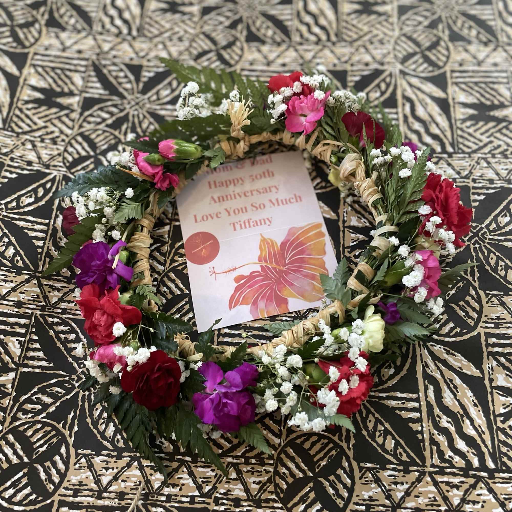 Floral wreath with pink, red, and purple flowers around a card
