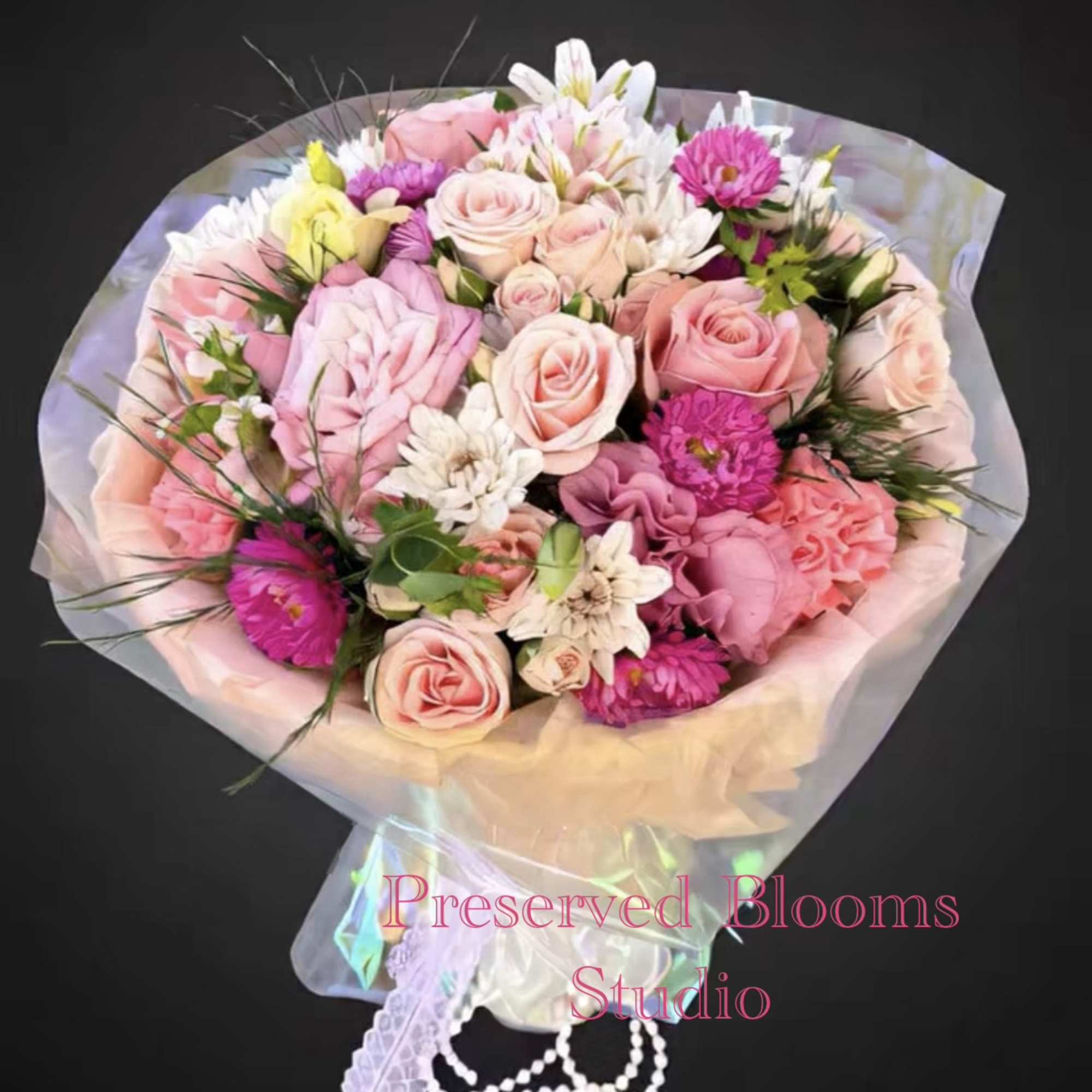 Pink and white bouquet of roses and mixed blooms wrapped in sheer paper