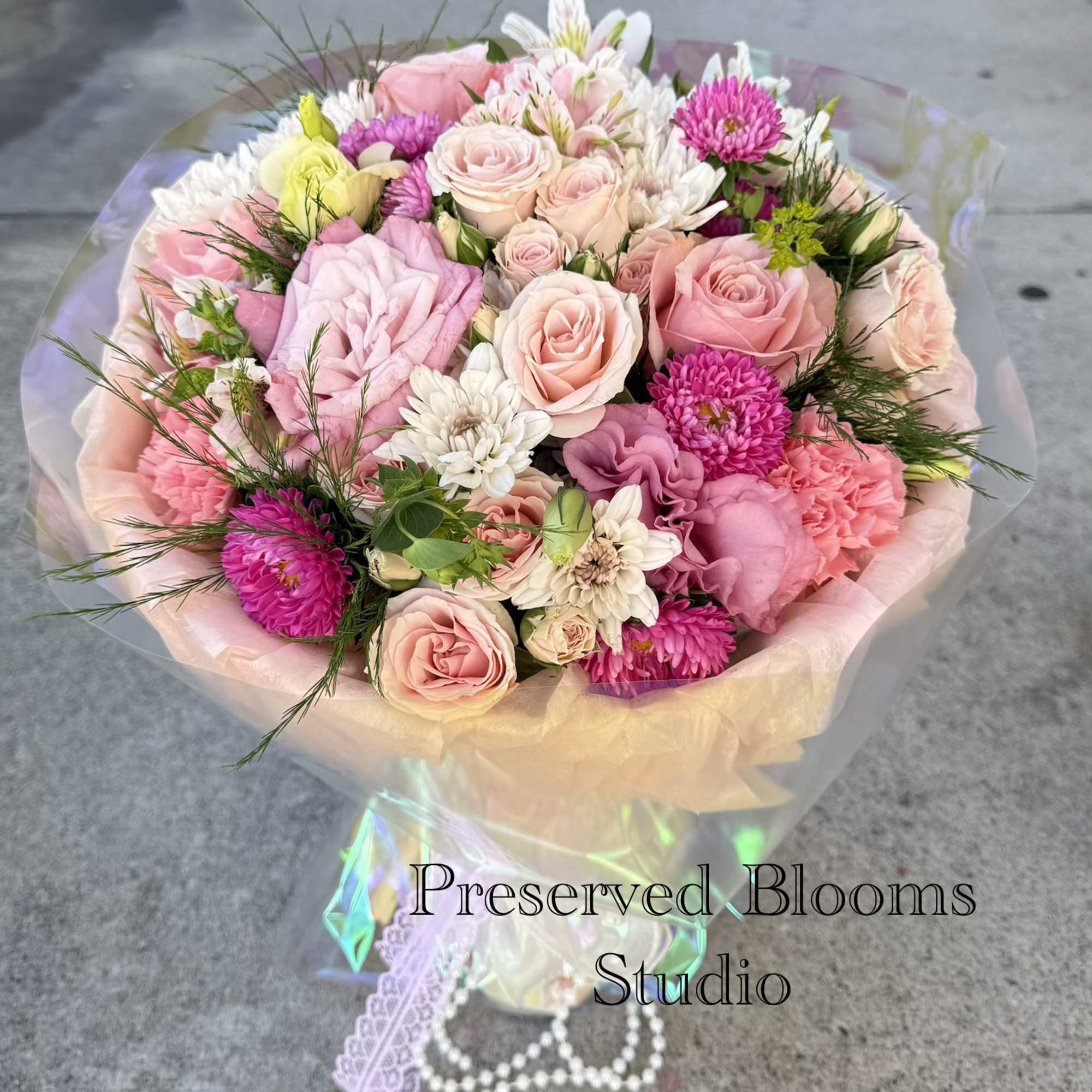 Bouquet of pink and white roses with mixed blooms wrapped in pastel paper