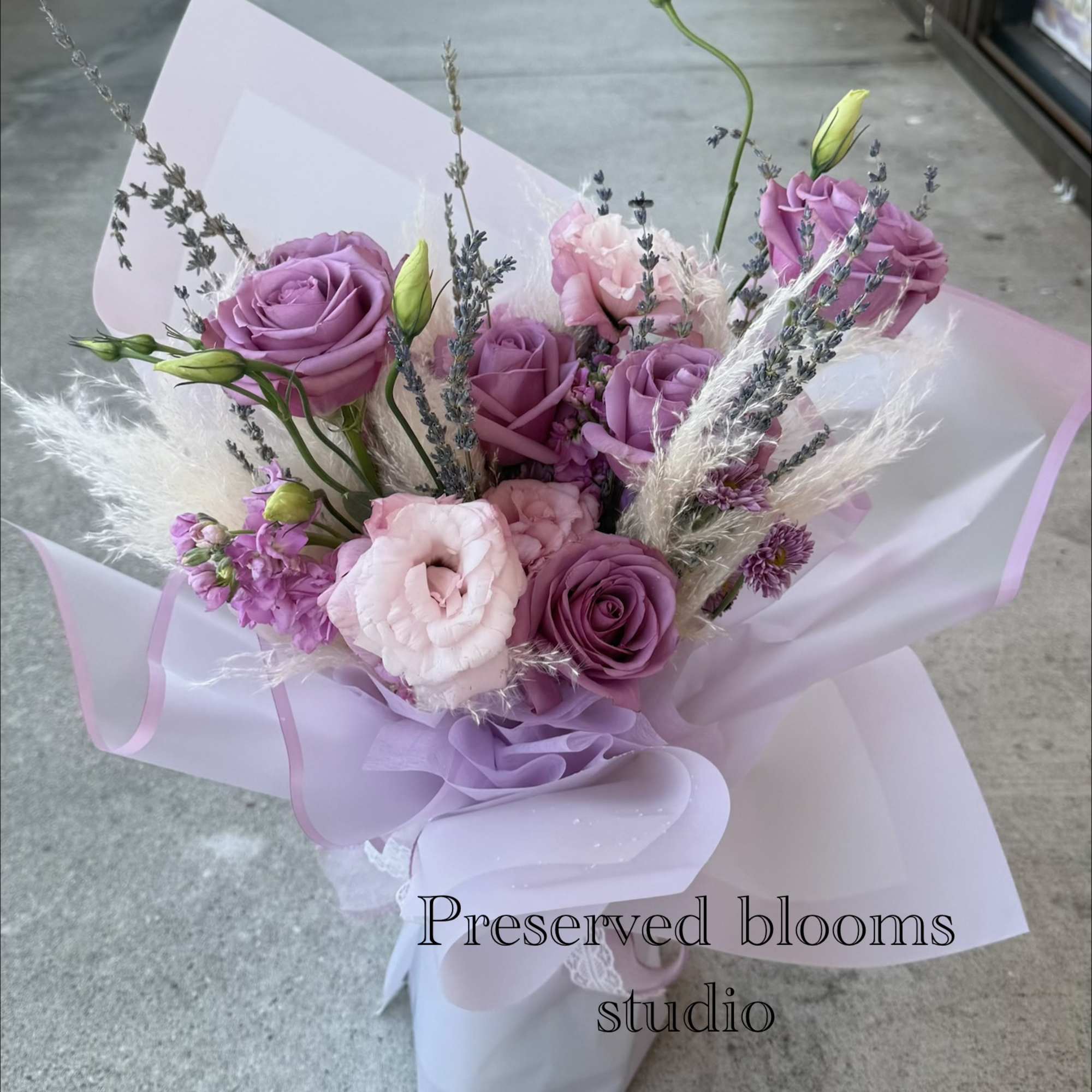 Lavender and pink bouquet of roses and lisianthus wrapped in pale paper
