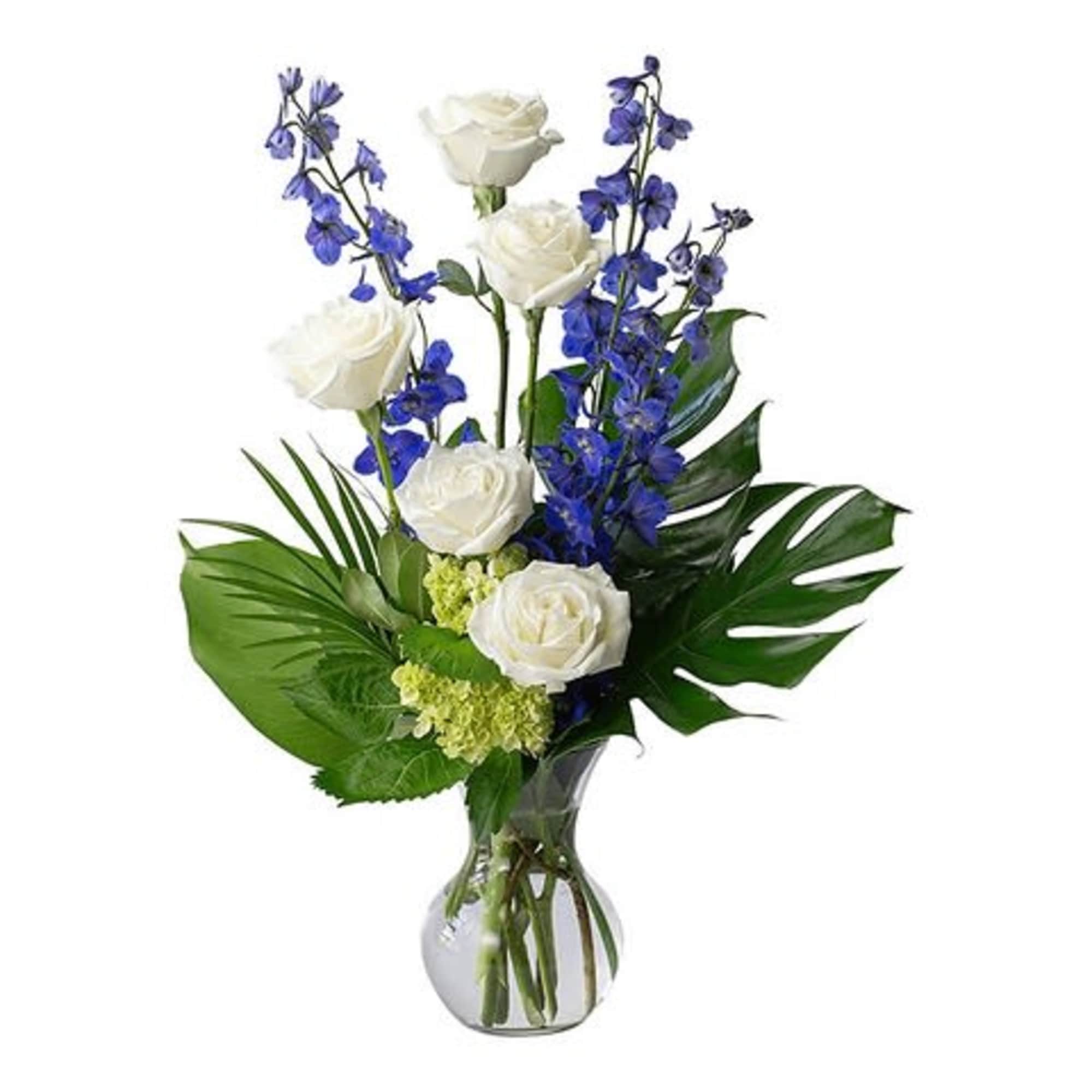 White roses and blue flowers in a clear glass vase